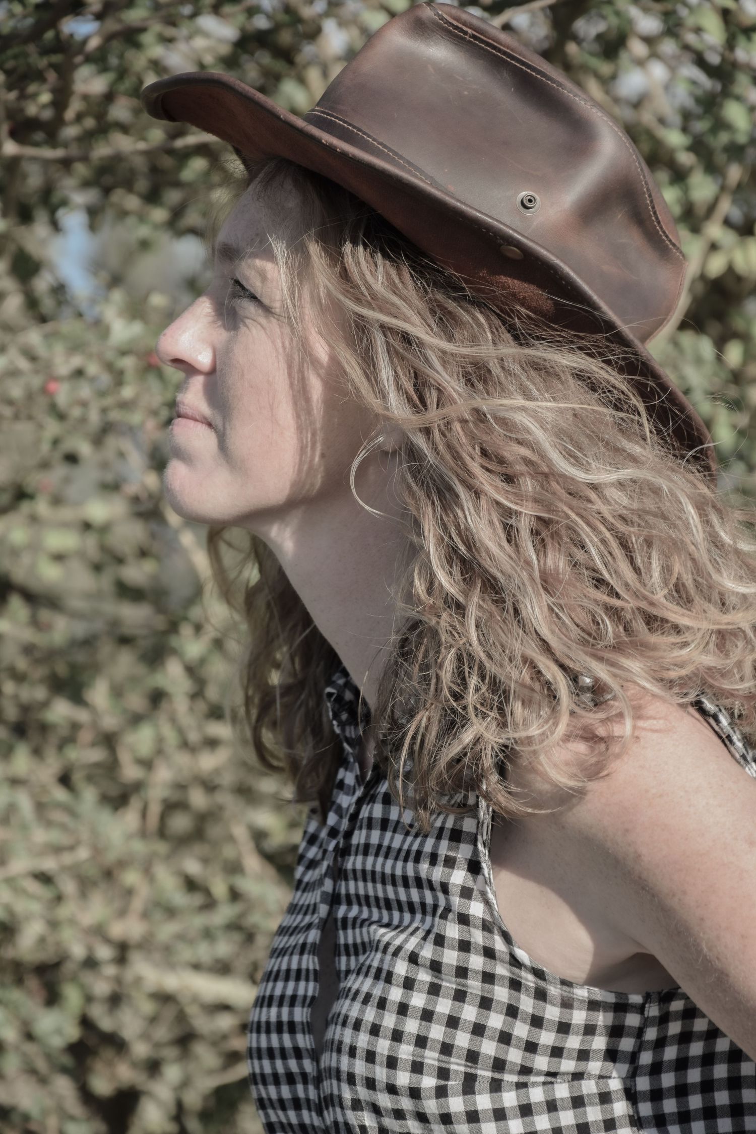 Profile shots wearing a brown cowboy hat and black and white checkered top.