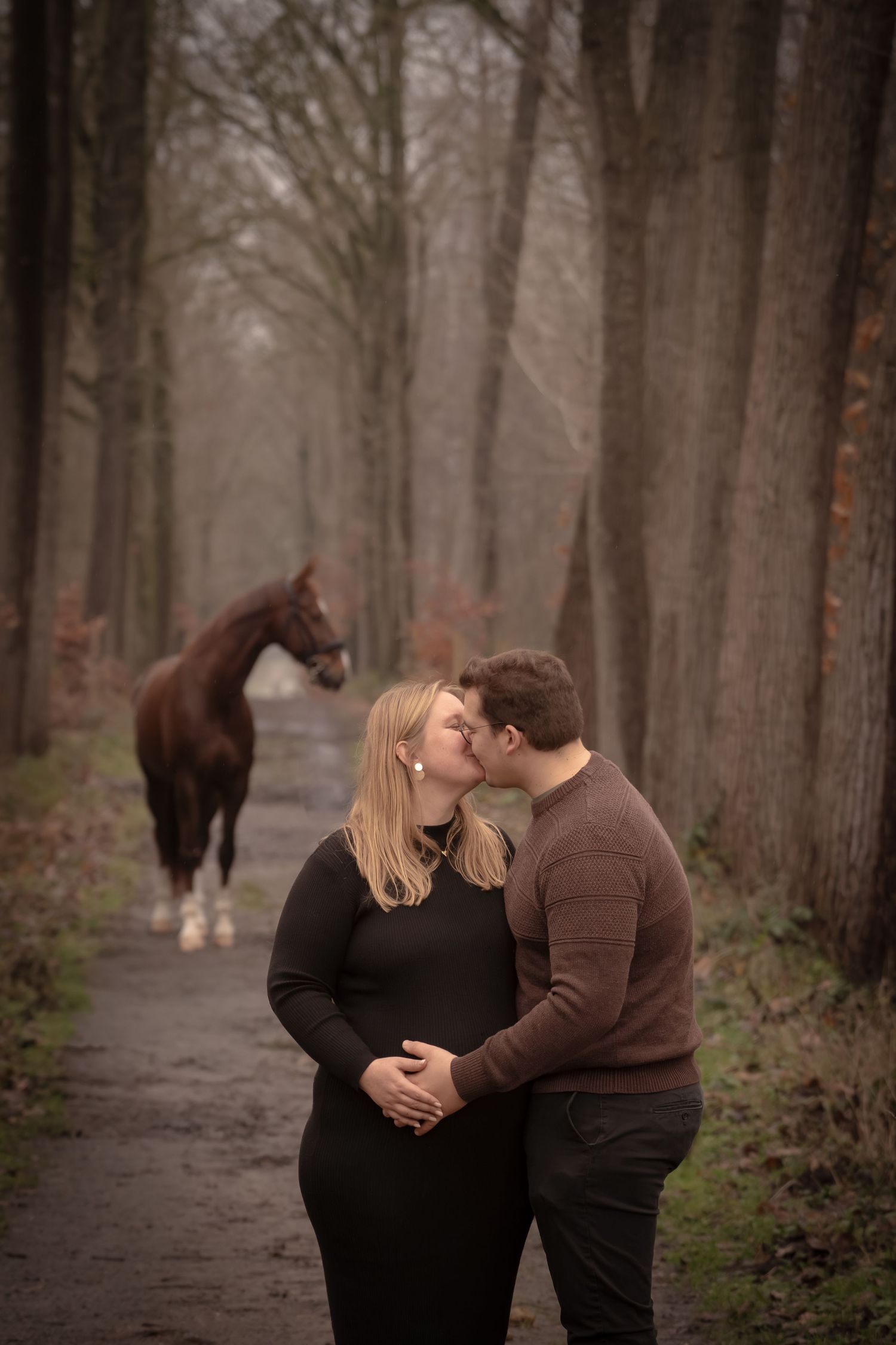 A couple shares an intimate moment while walking through a misty forest path on an autumn day.