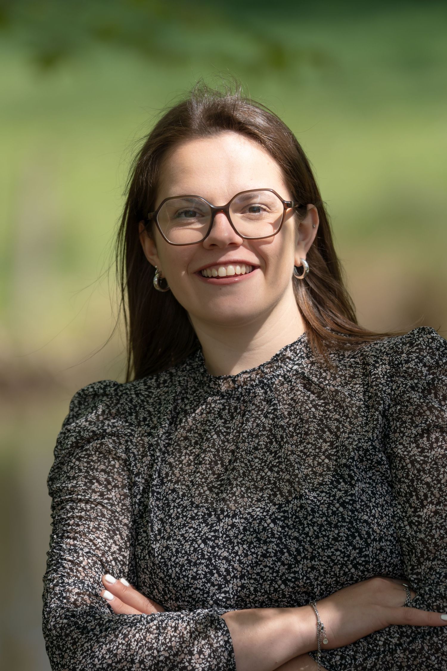 Professional outdoor portrait of someone in a textured grey sweater with glasses.
