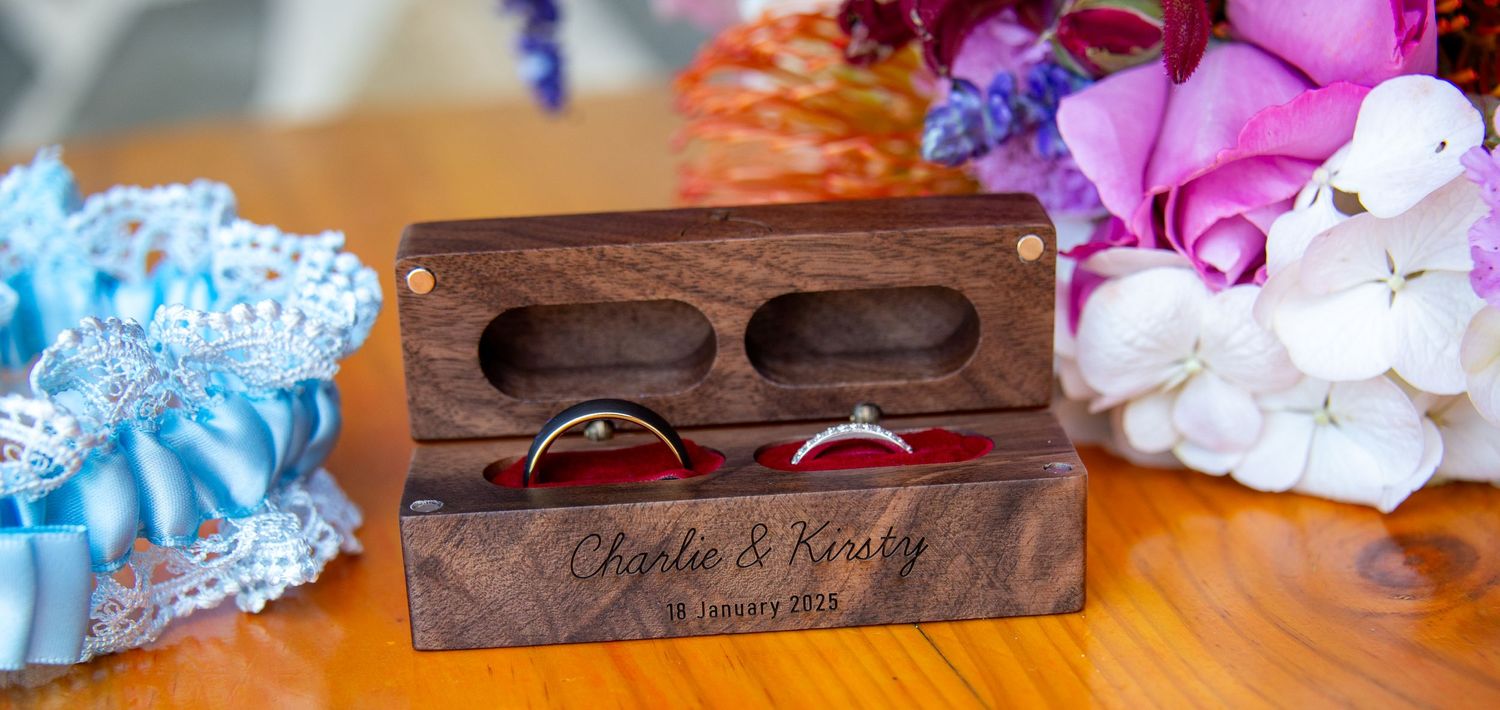 Wooden ring box with floral decorations and garters on table.