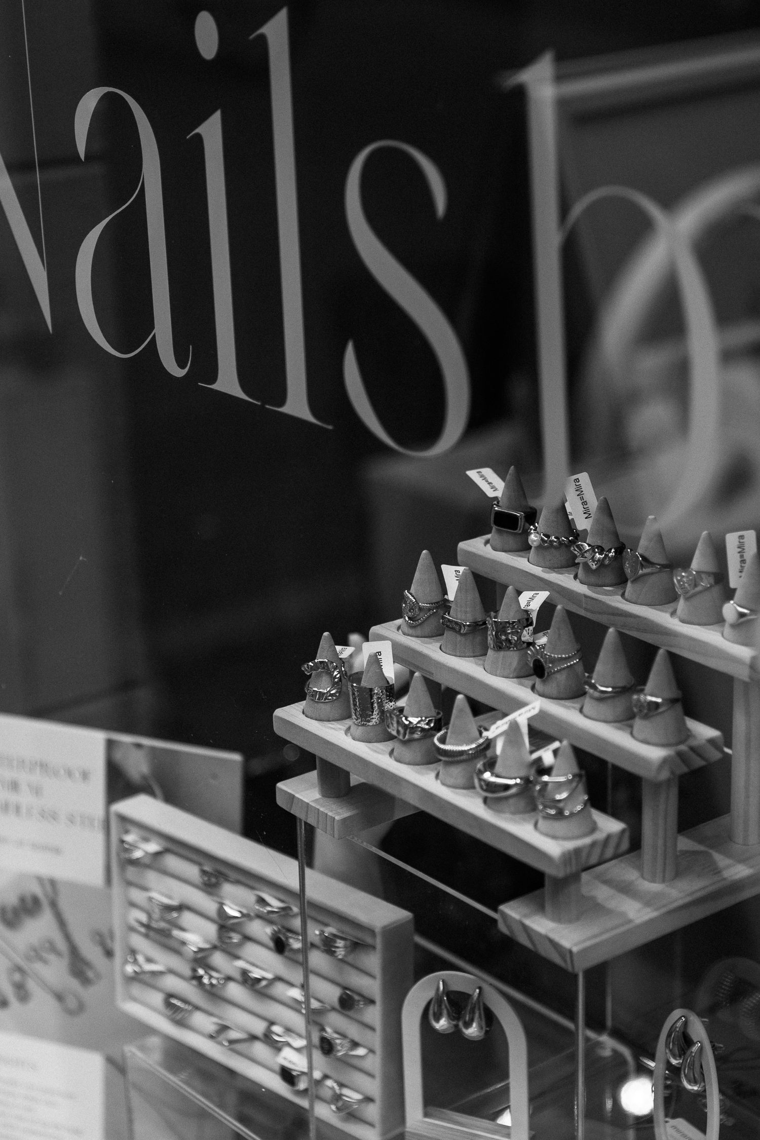 Black and white photo of a nail salon display window with jewelry and accessories.