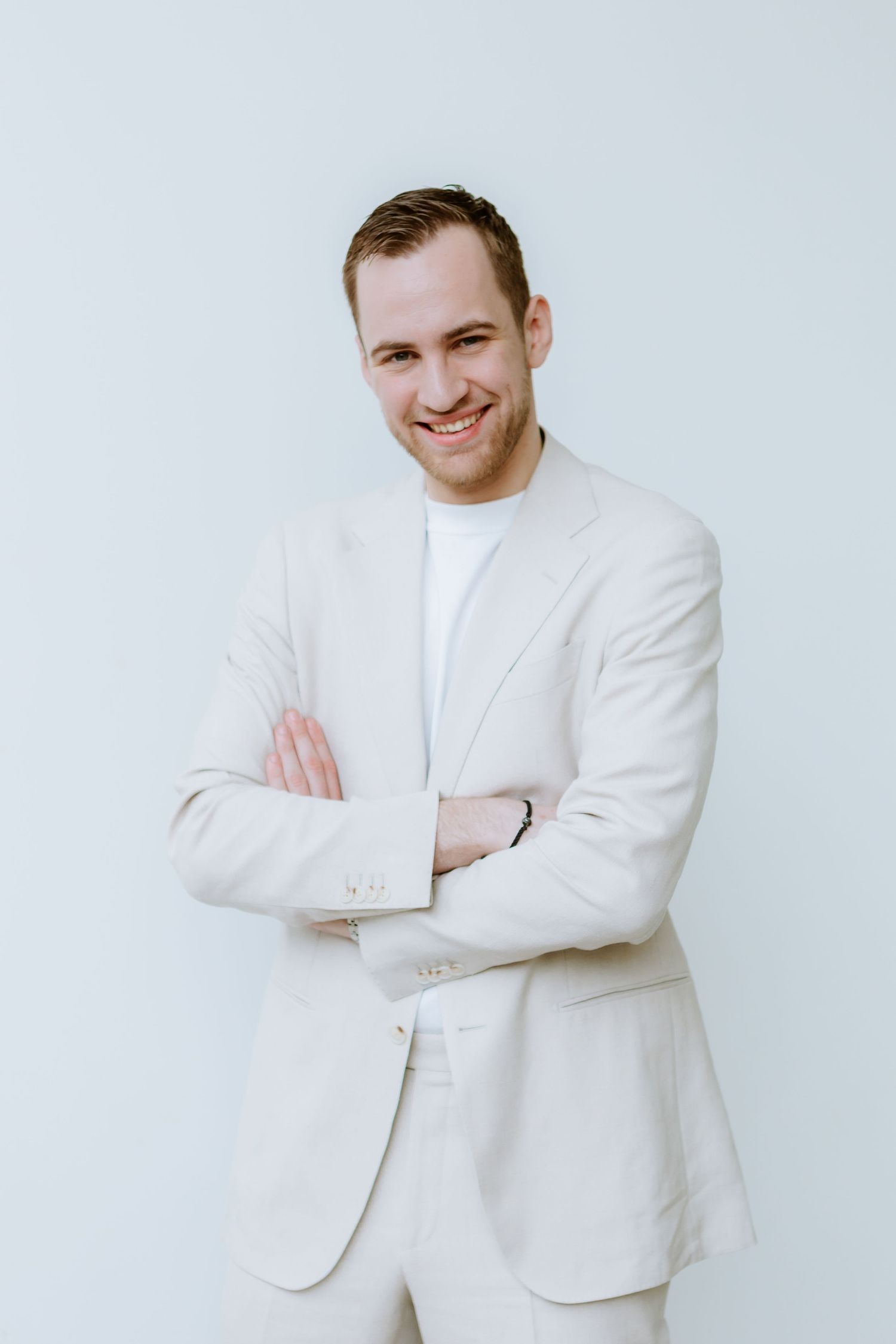 Professional headshot of a person in white suit against minimal background.