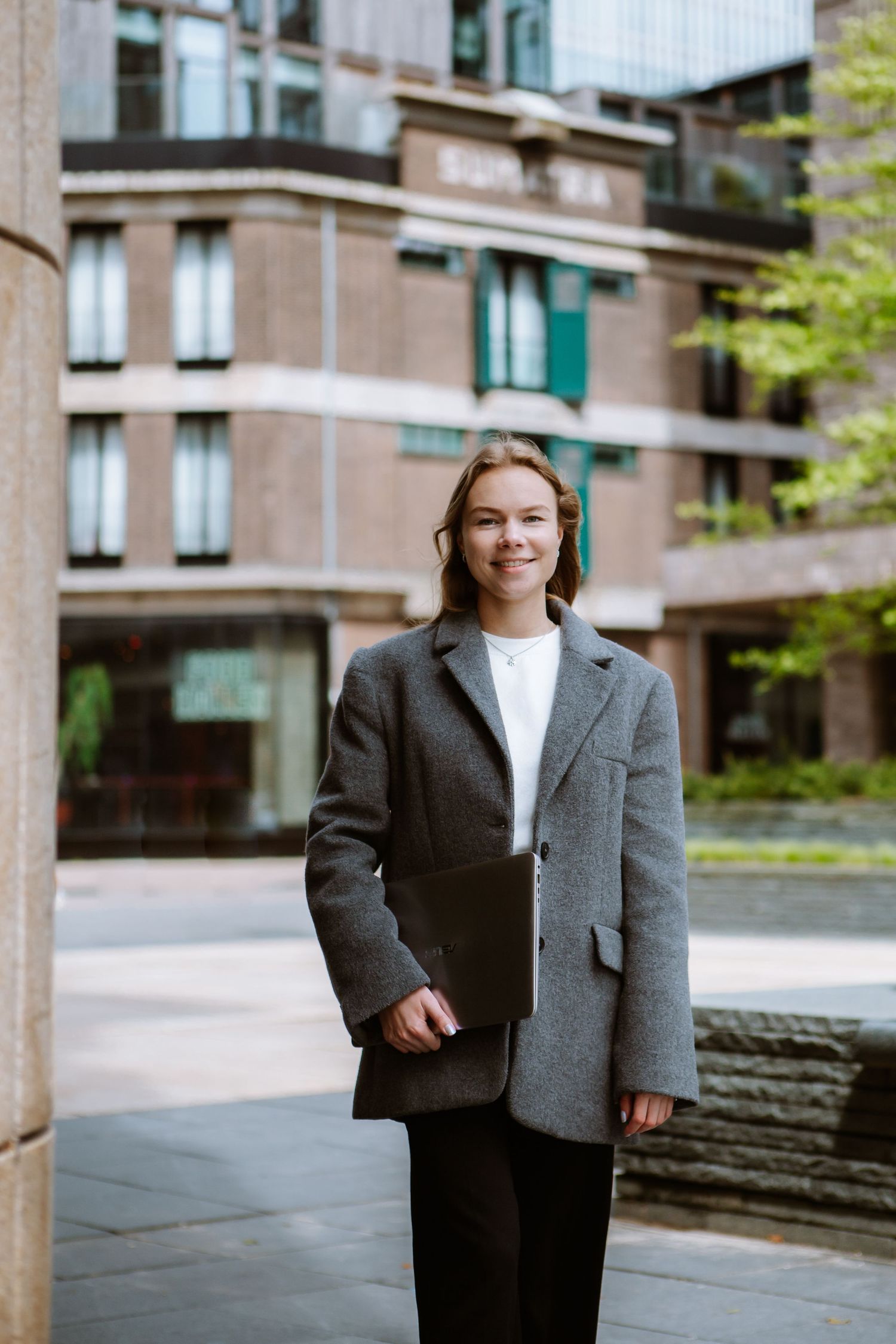 Professional wearing oversized grey blazer and white t-shirt in urban setting.