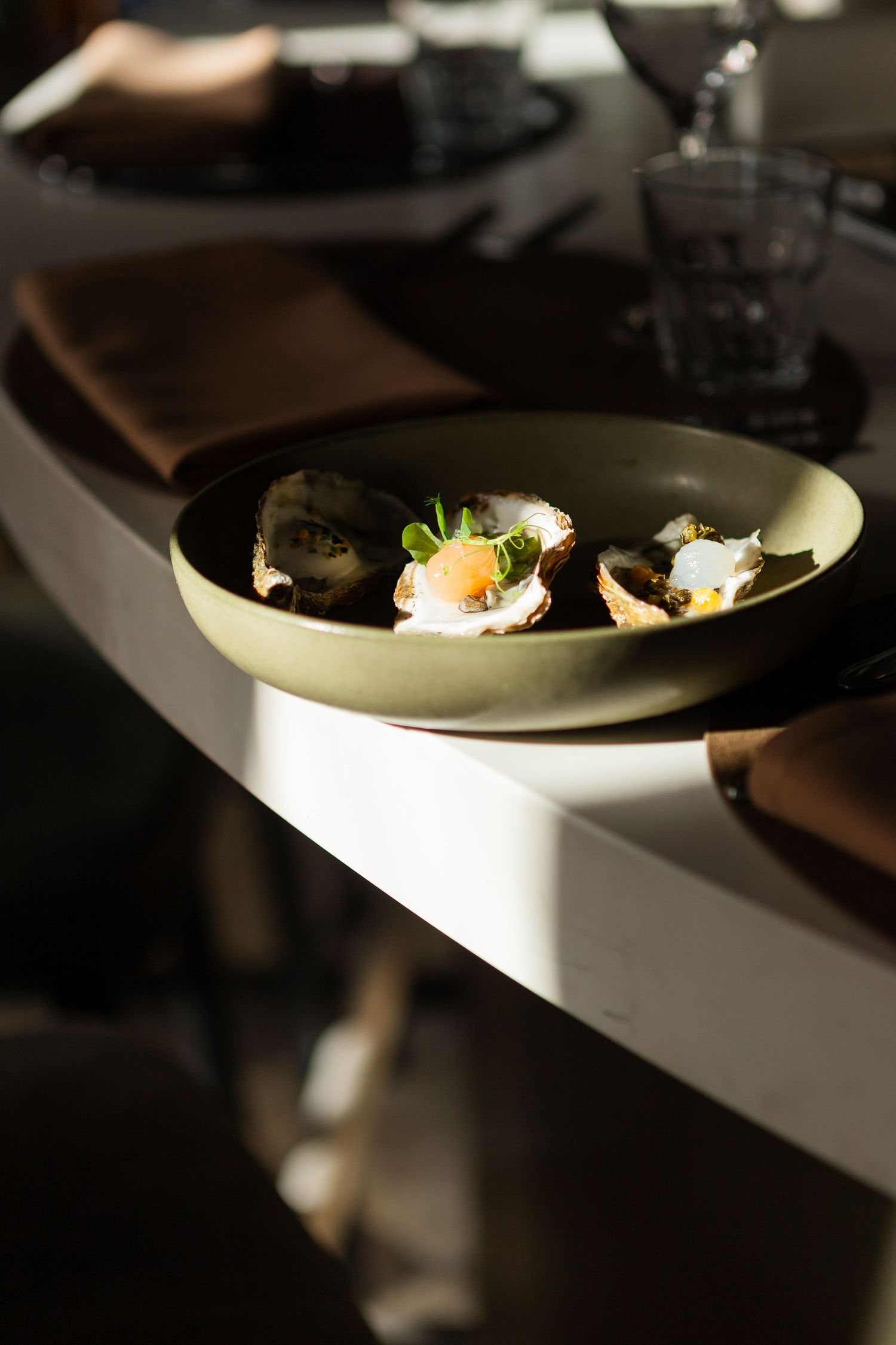 Small appetizers presented on a sage green plate in dramatic side lighting.