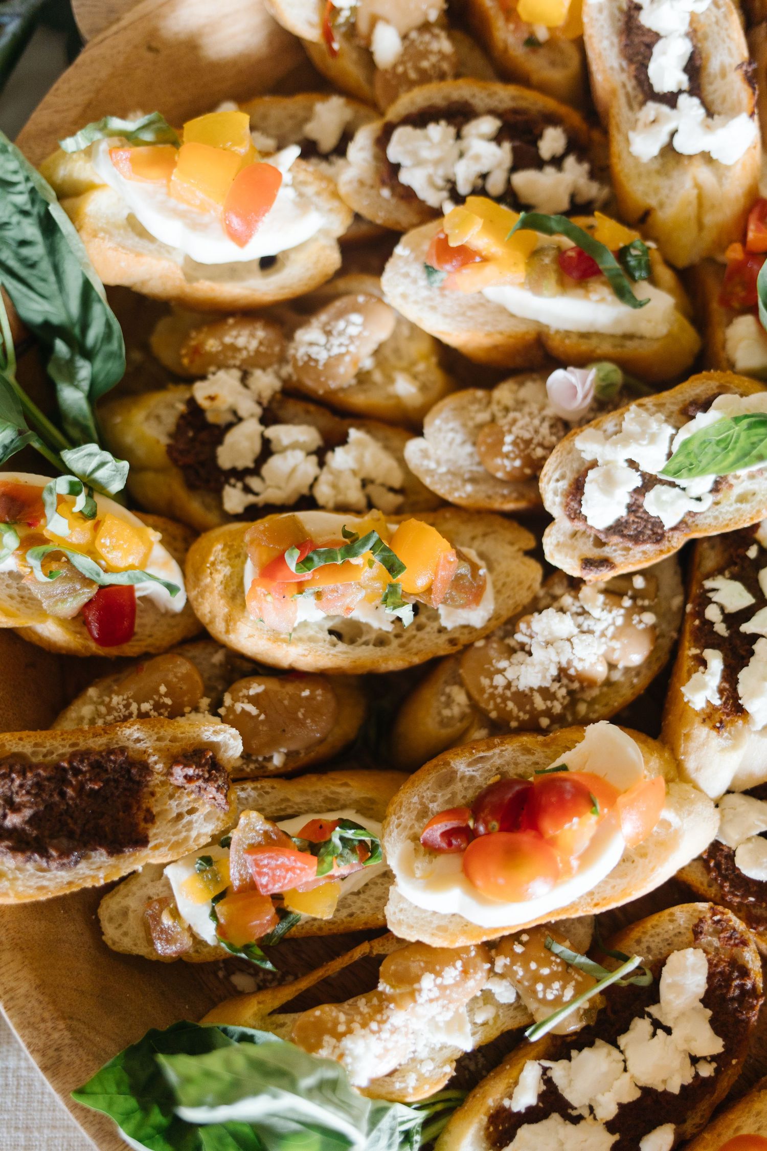 Assorted gourmet bruschetta appetizers topped with smoked salmon, fresh herbs, and crumbled cheese on rustic platter.
