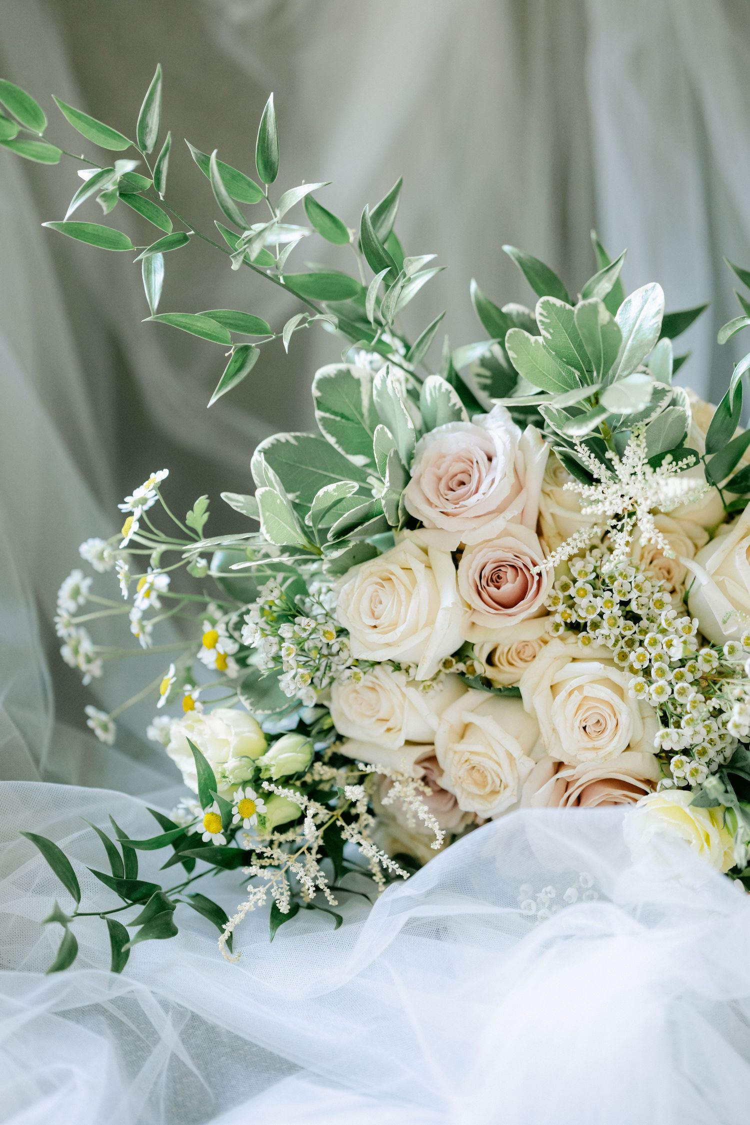 Elegant bridal bouquet with blush roses, white wildflowers, and green eucalyptus on soft tulle fabric. - Youngblood Vineyard Wedding