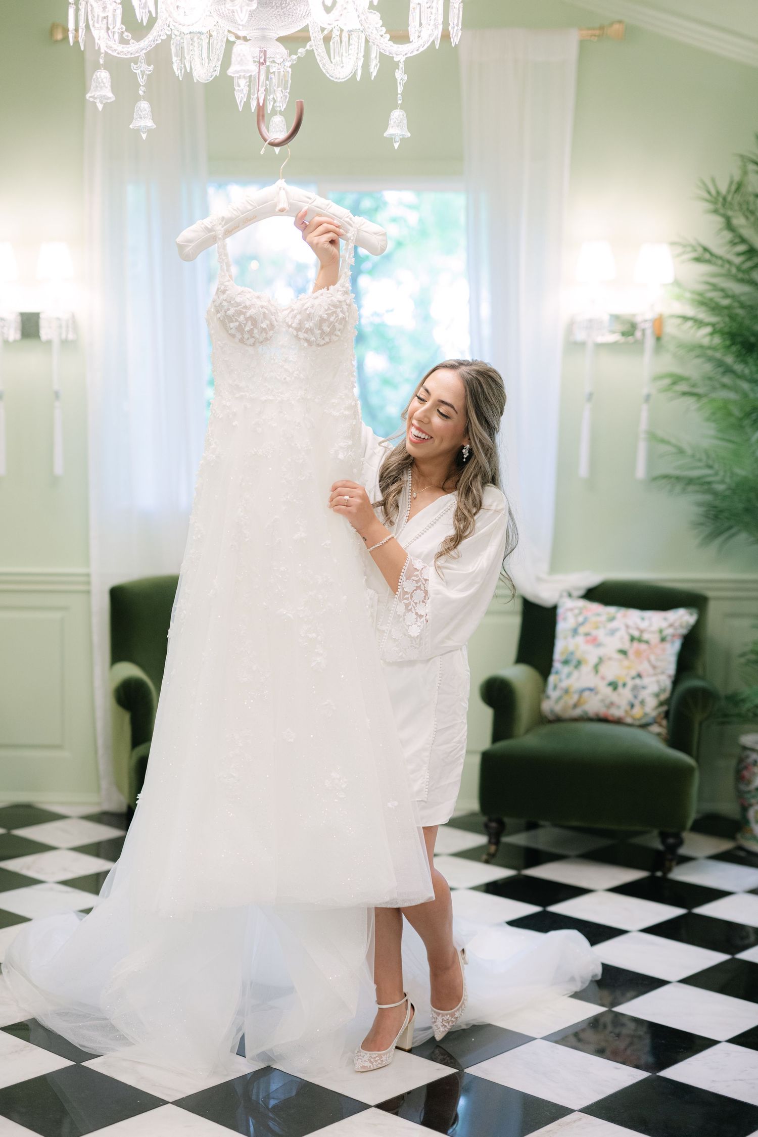 Someone in a white dress twirls playfully on a black and white checkered floor under an elegant crystal chandelier. - Meyer's Castle Events