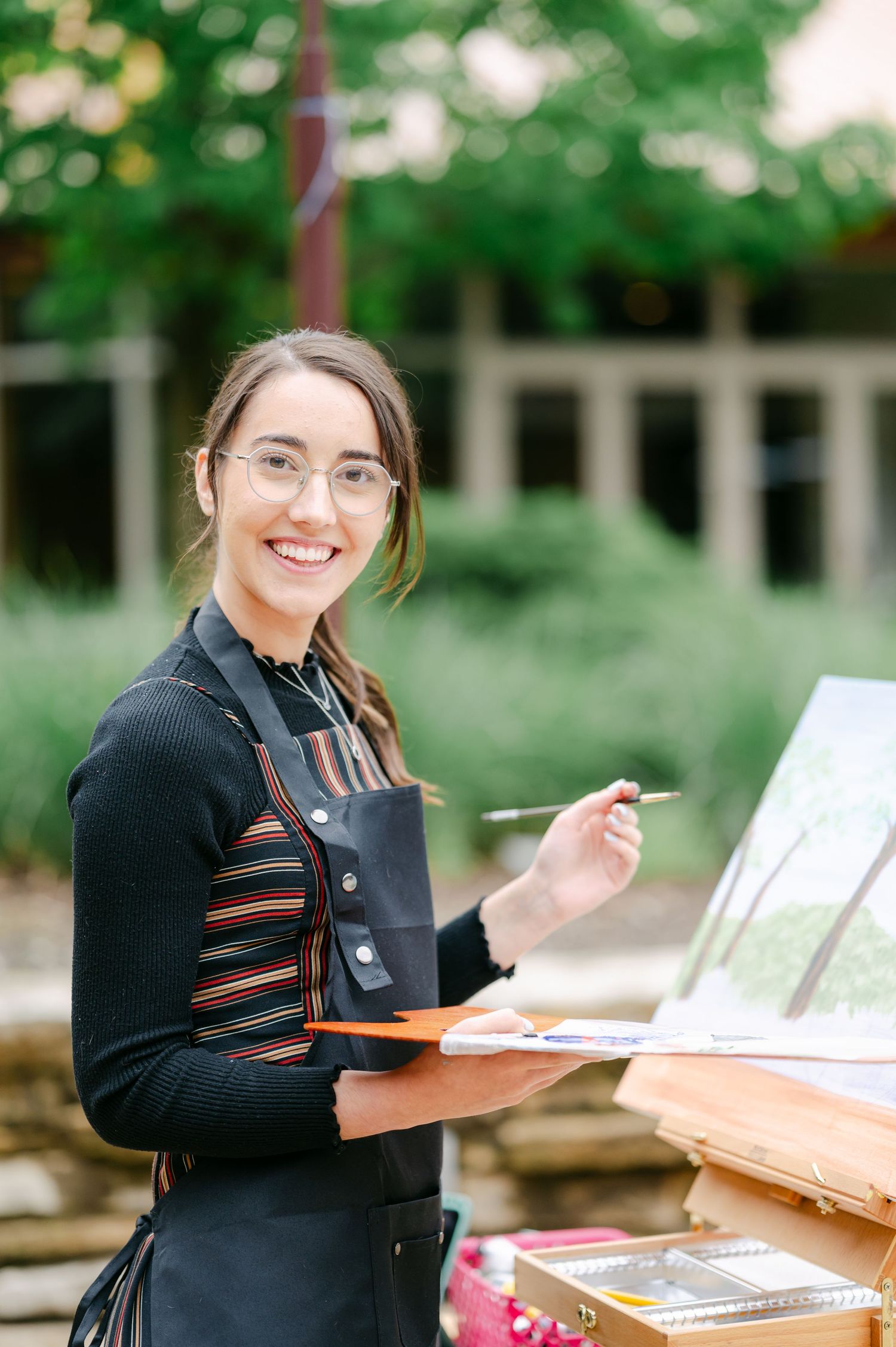 Student studying outdoors with textbooks and papers spread on wooden table in park setting. - Hyatt Lodge Oak Brook