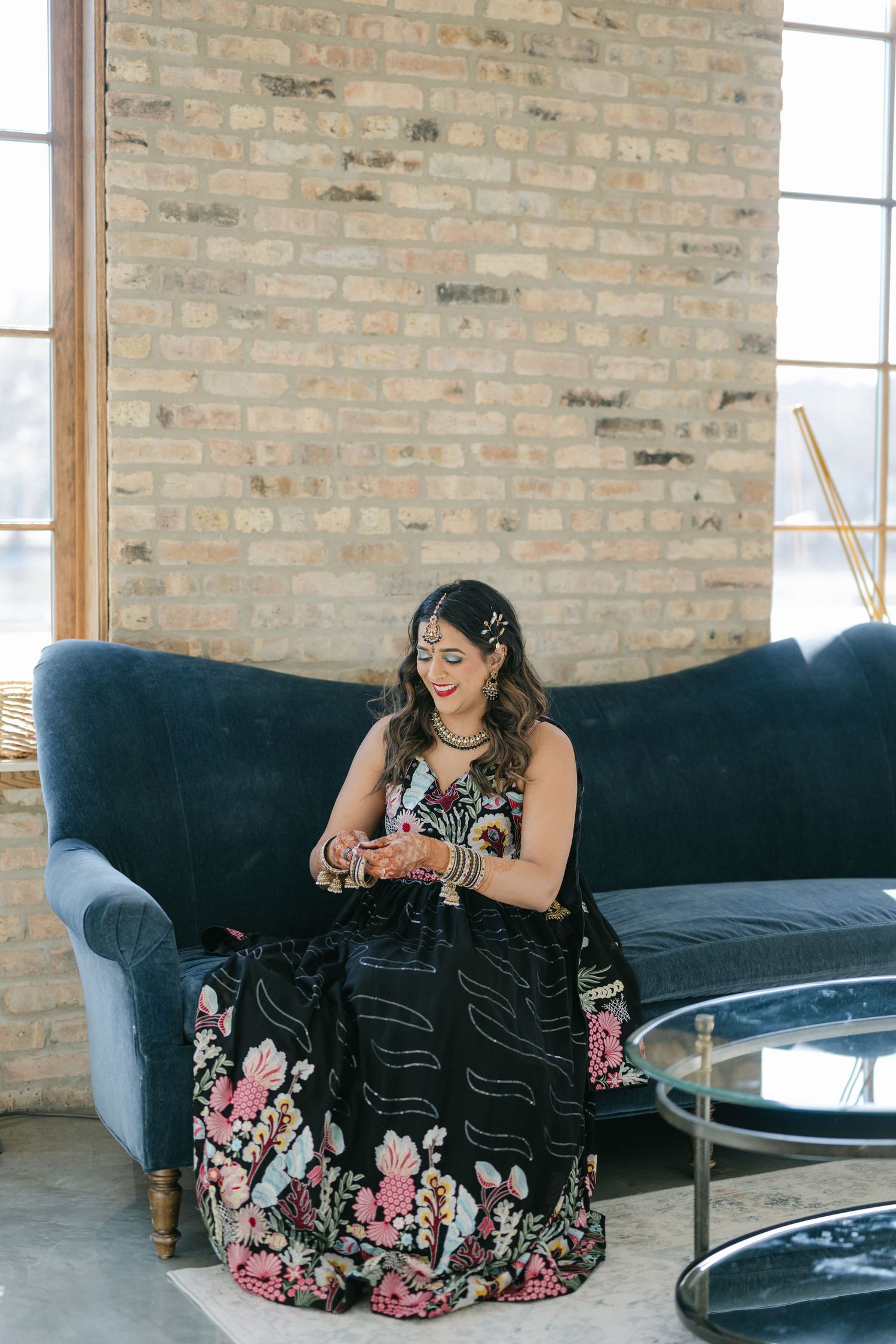 A person in a floral dress sits on a dark blue couch in a modern industrial space with exposed brick walls. - The Brix on the Fox