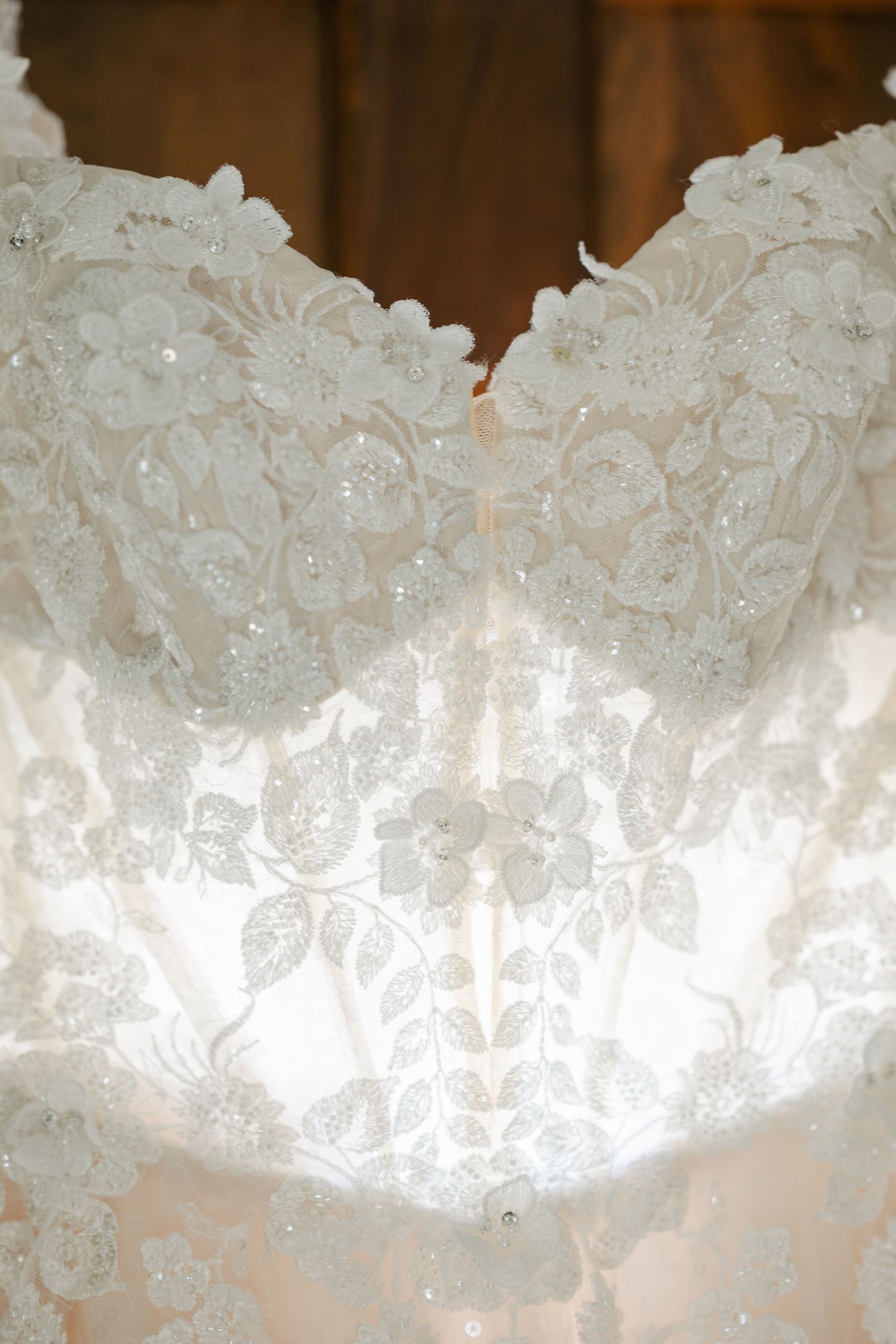 Close-up of an elegant beaded lace wedding dress bodice with intricate floral embroidery details. - Youngblood Vineyard Wedding