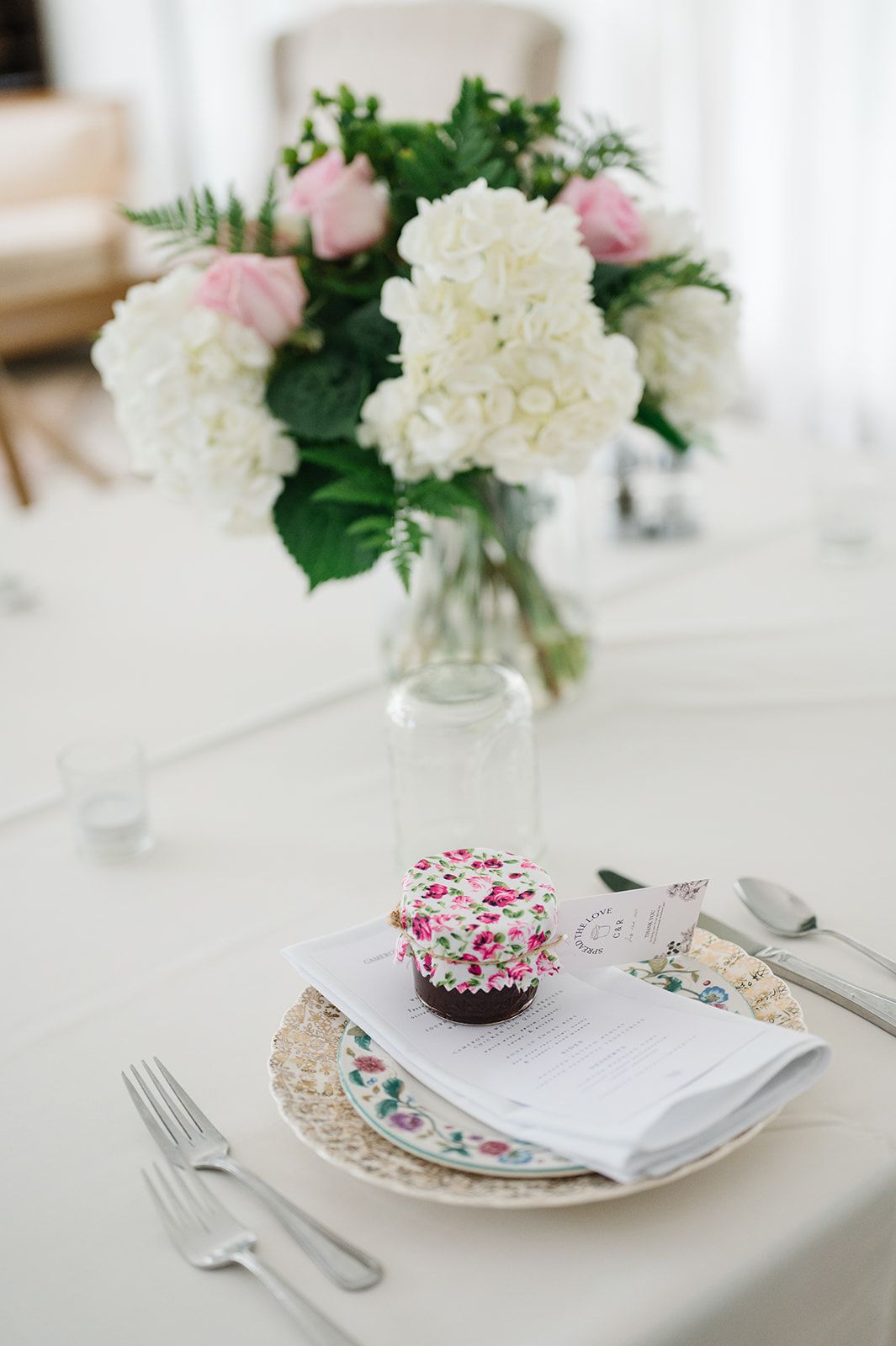 Elegant wedding table setting with floral cupcake, vintage plate, silverware, and white hydrangea centerpiece. - Heritage Prairie Farm