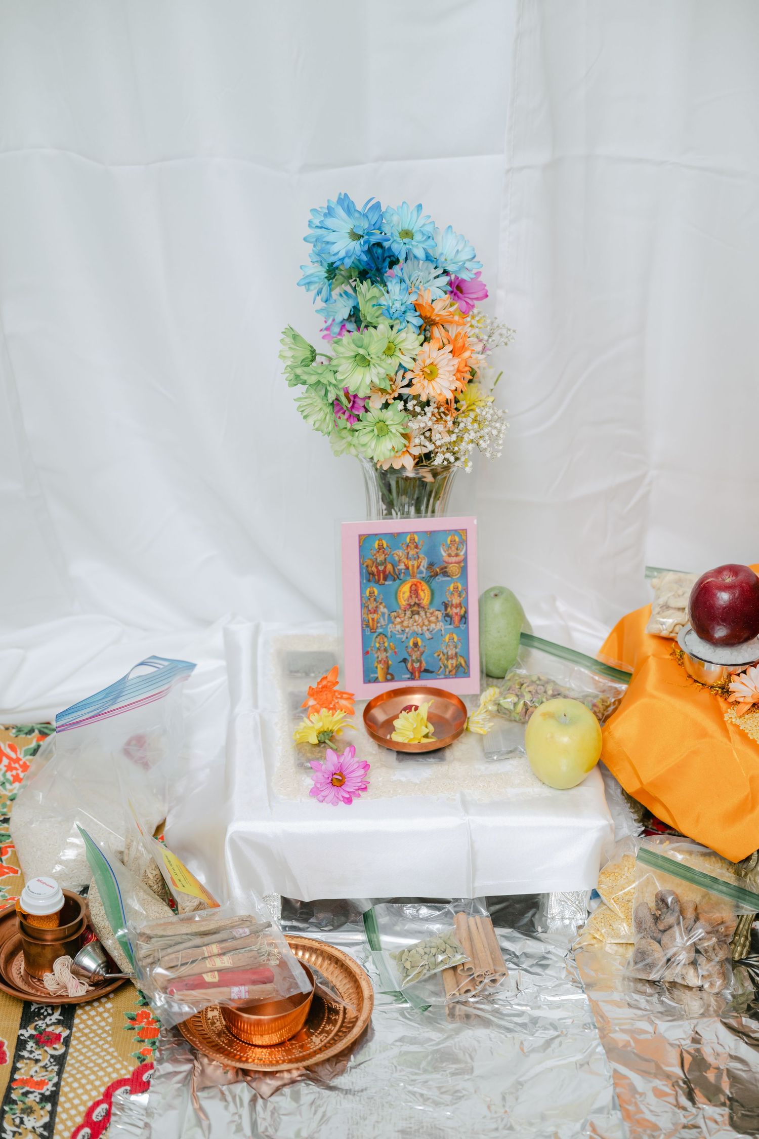 The Brix on the Fox Wedding - Colorful floral arrangement in a decorative vase sits on a table with scattered items and an orange cloth.