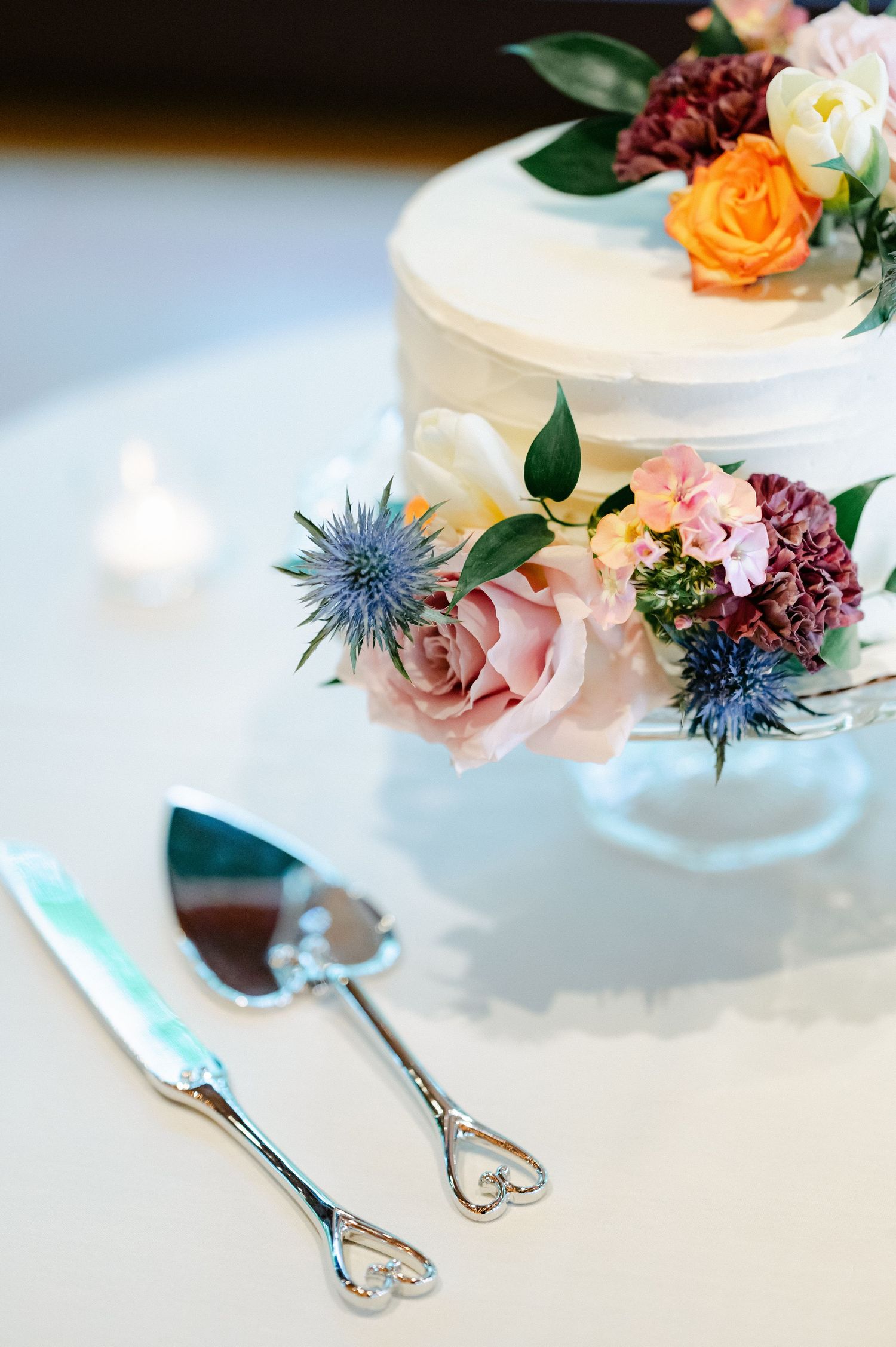Elegant table setting with white plates adorned with colorful flowers and silver cutlery on a light surface. - Hyatt Lodge Oak Brook
