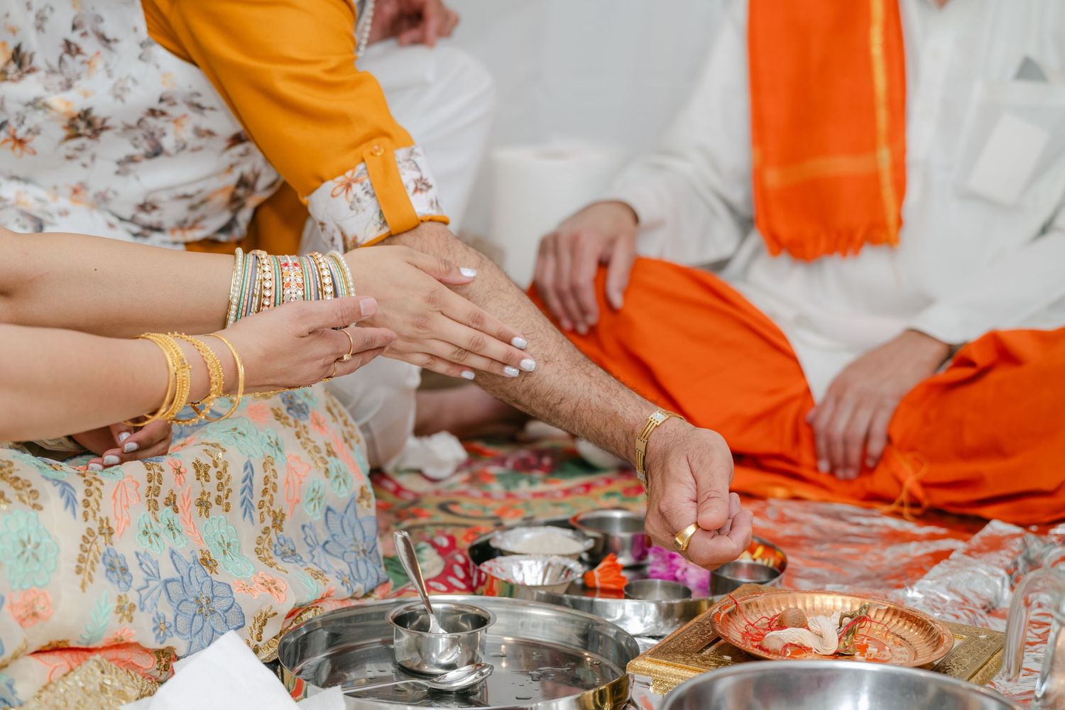 The Brix on the Fox Wedding - Hands preparing traditional Indian food and spices on metal plates during a cooking ceremony.