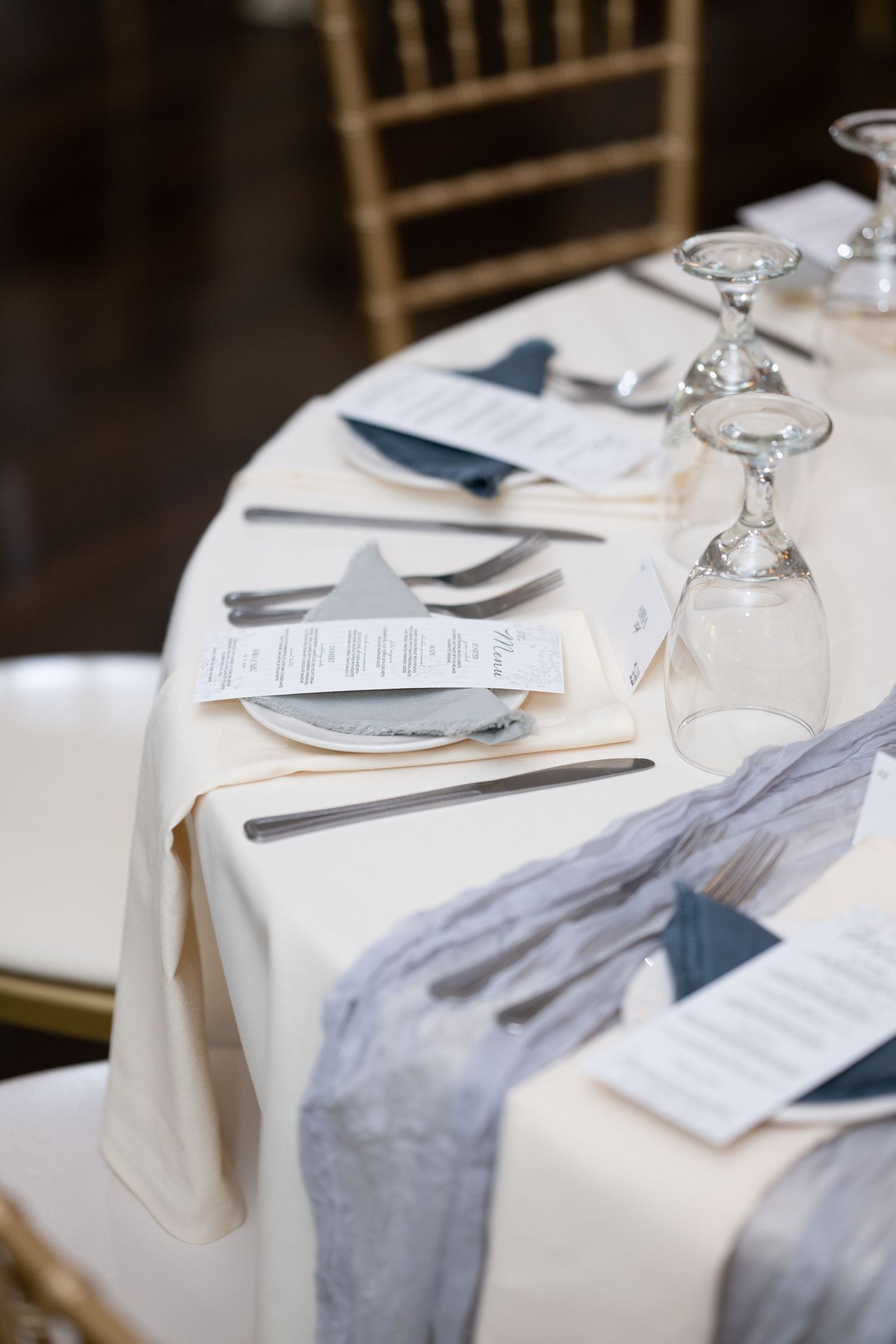 Elegant table settings with white linens, crystal glasses, and navy blue napkins arranged for a formal dining event. - Meyer's Castle Events
