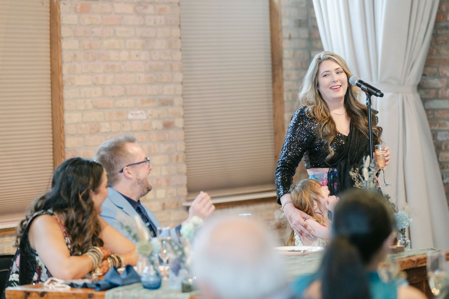 People gather around tables at an indoor event with exposed brick walls and natural lighting. - The Brix on the Fox