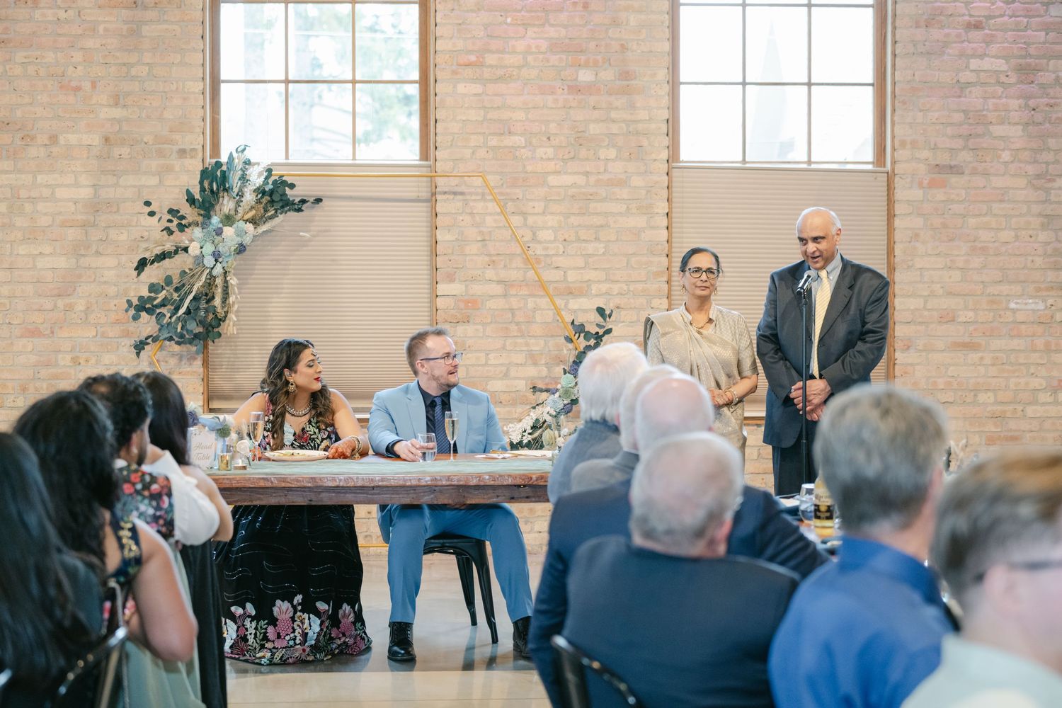 Business professionals seated at tables engage in discussion during a meeting in a brick-walled conference space. - The Brix on the Fox