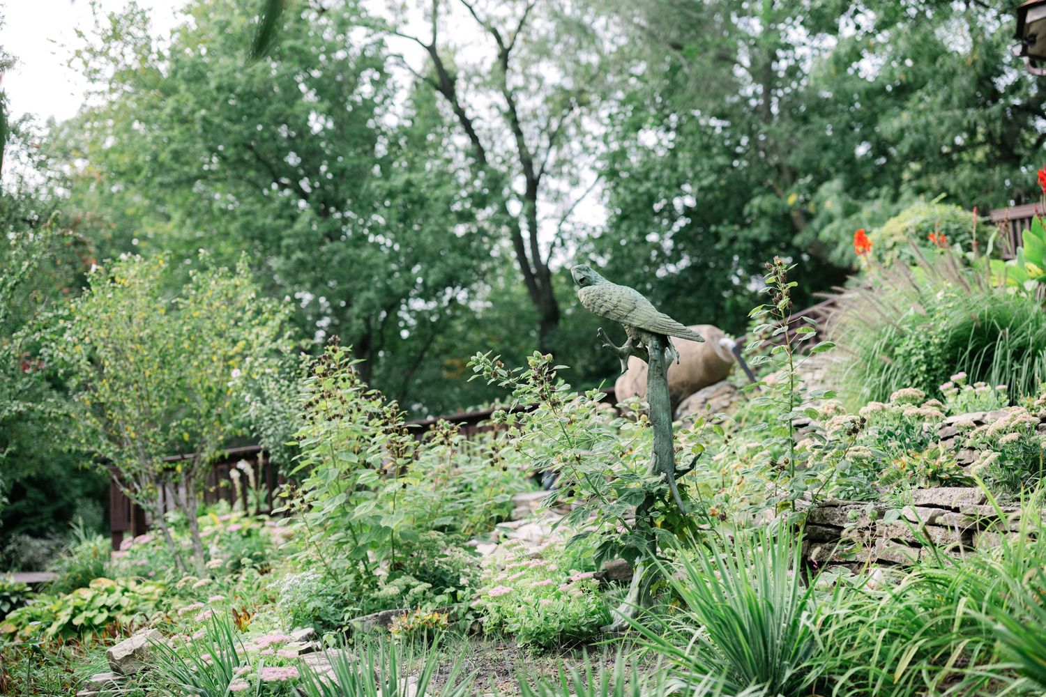 A lush garden path winds through green foliage and flowering plants on a summer day. - Meyer's Castle Events