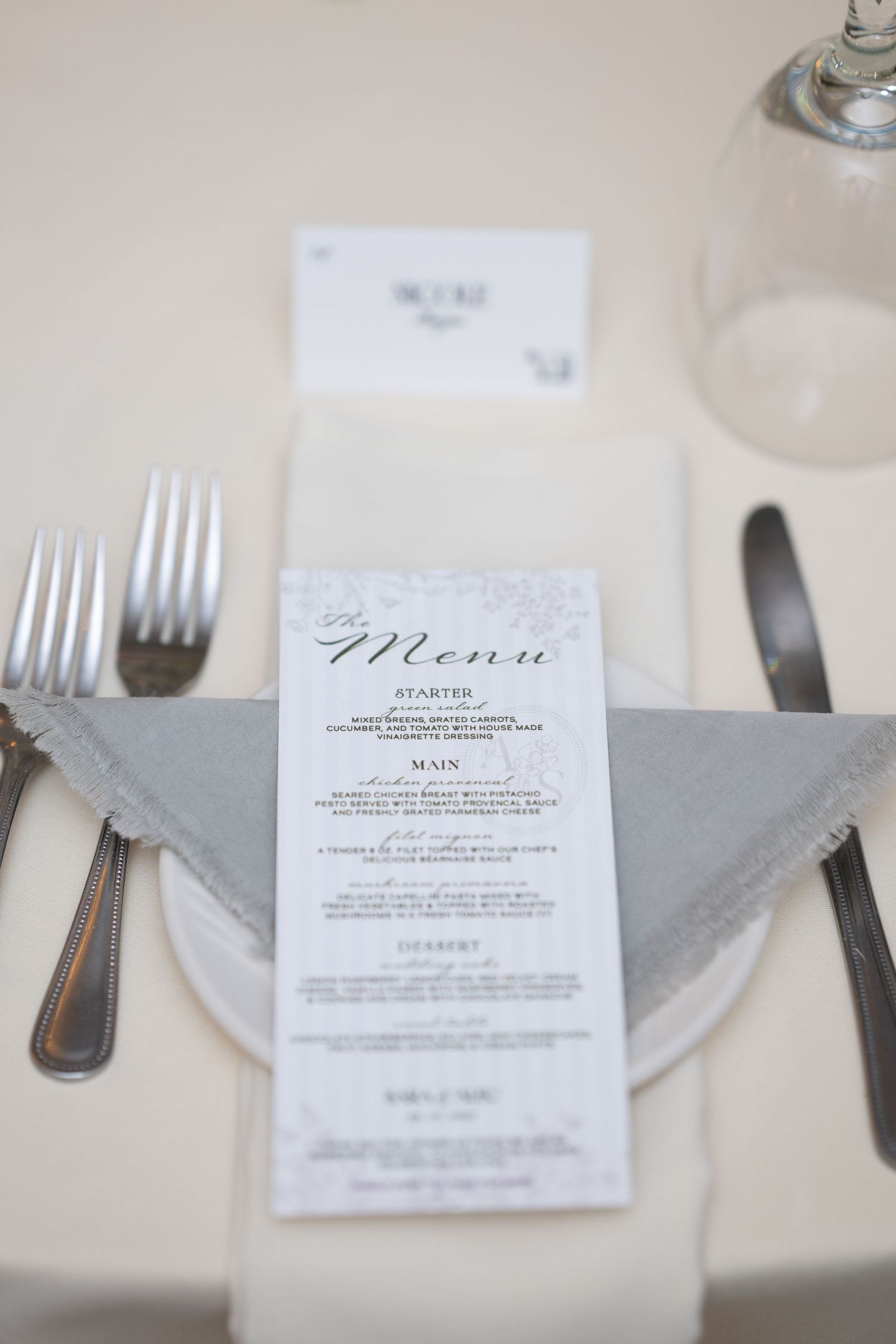Elegant table setting with white menu cards, silver cutlery, and gray linen napkins at a formal dining event. - Meyer's Castle Events