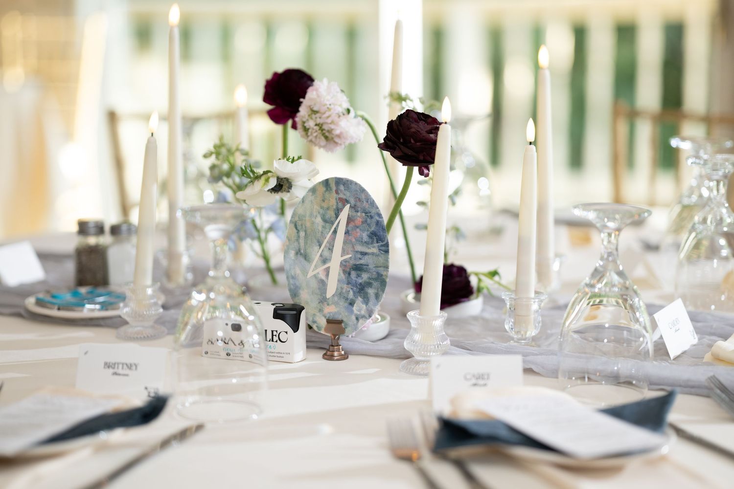 Elegant table settings with white candles, crystal glasses, and delicate floral arrangements at a formal event. - Meyer's Castle Events