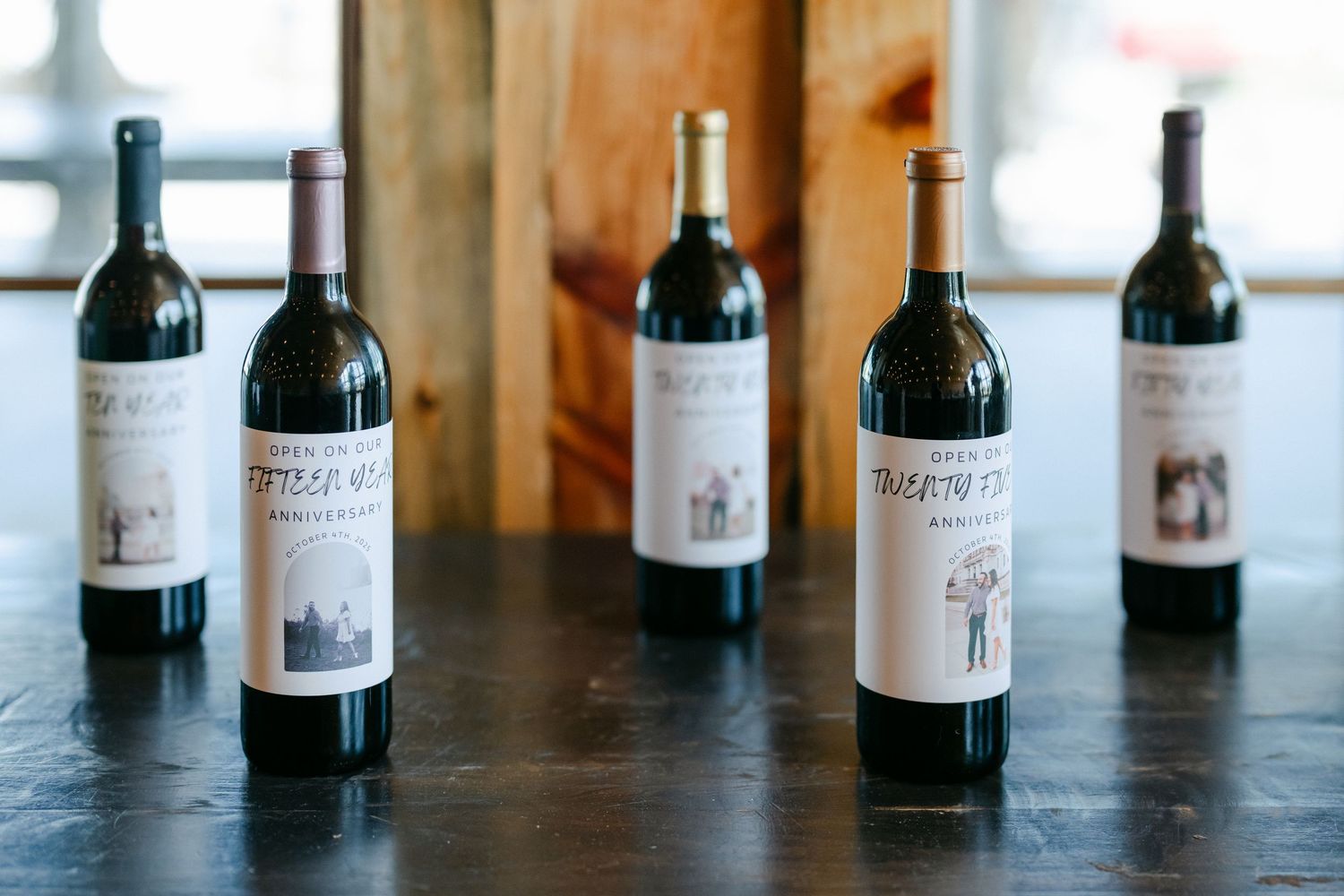 Five bottles of Prisoner Wine Company red wine displayed on a dark wooden table in a rustic tasting room. - Youngblood Vineyard Wedding