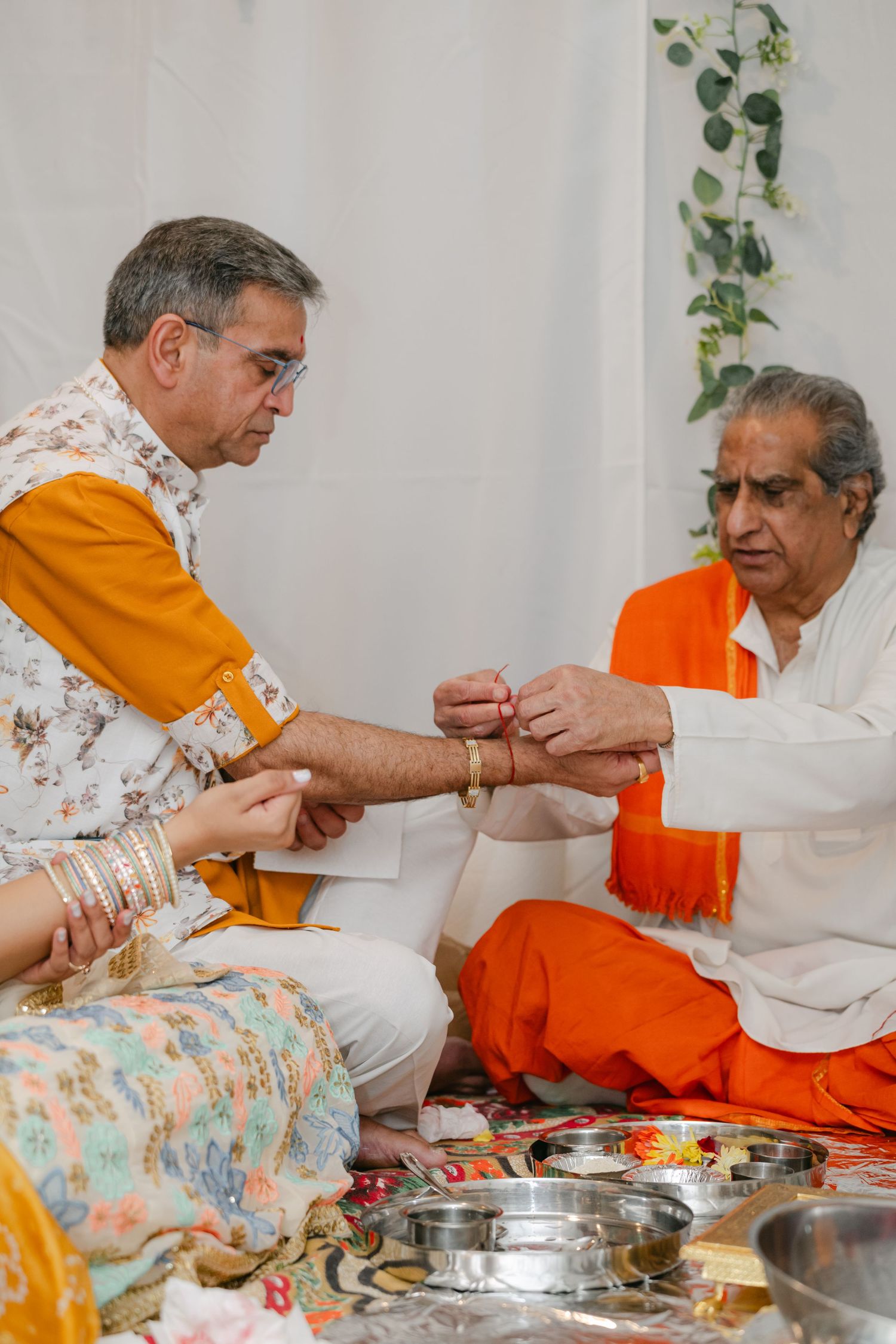 The Brix on the Fox Wedding - Two people in orange and white clothing sit together sharing a traditional Indian meal served on metal plates.