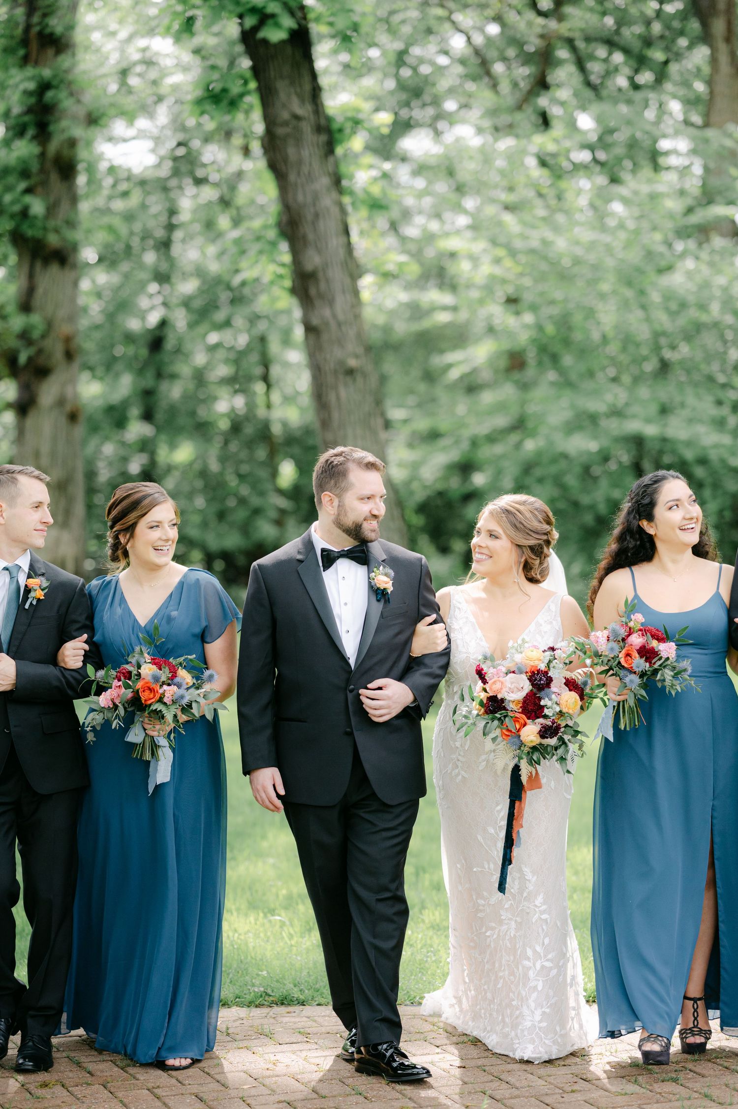 Wedding party in navy blue and black attire walking and laughing together on outdoor path. - Hyatt Lodge Oak Brook