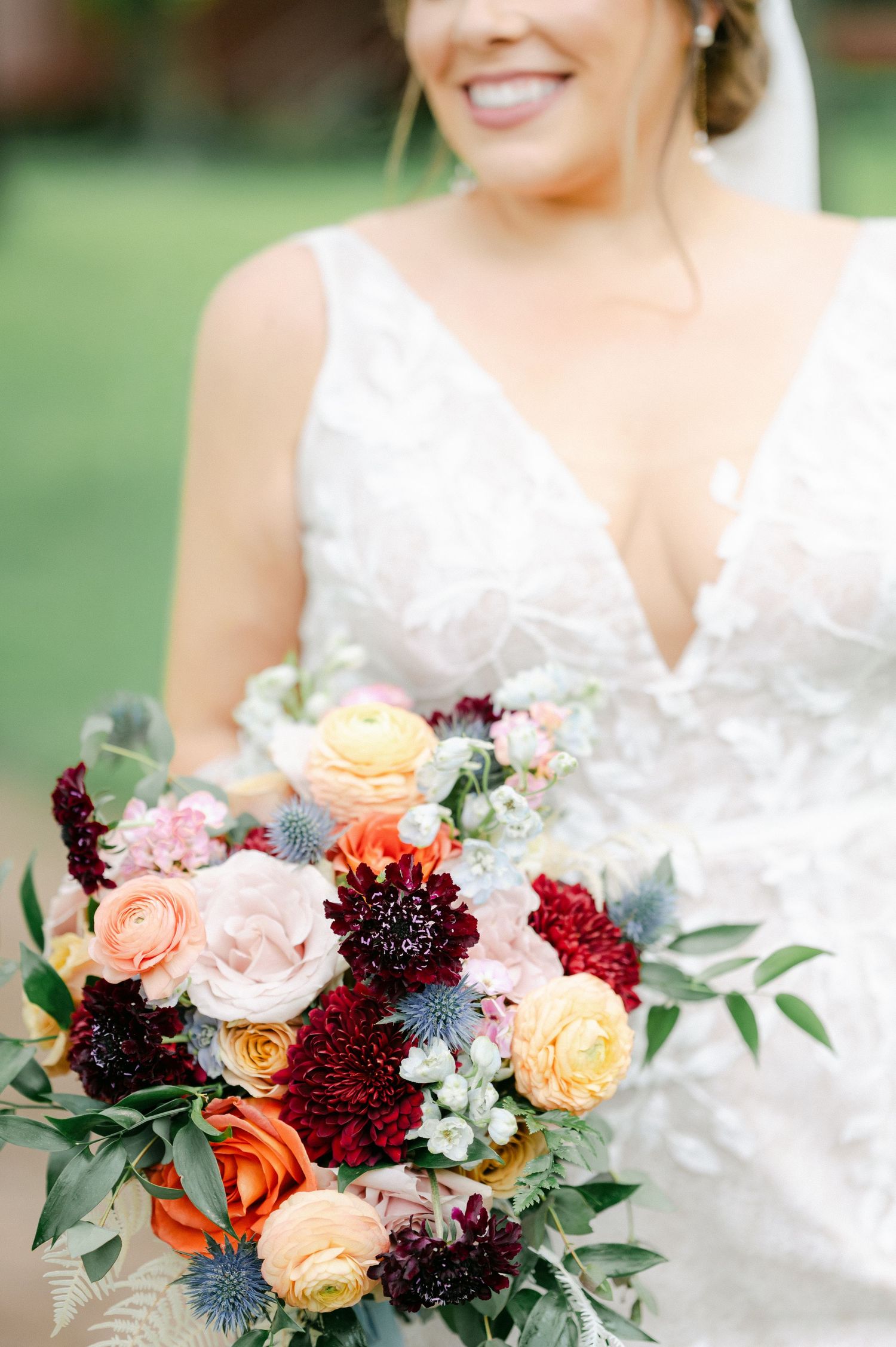 Wedding bouquet with burgundy dahlias, peach roses, and blue thistle creates a vibrant autumn-inspired arrangement. - Hyatt Lodge Oak Brook