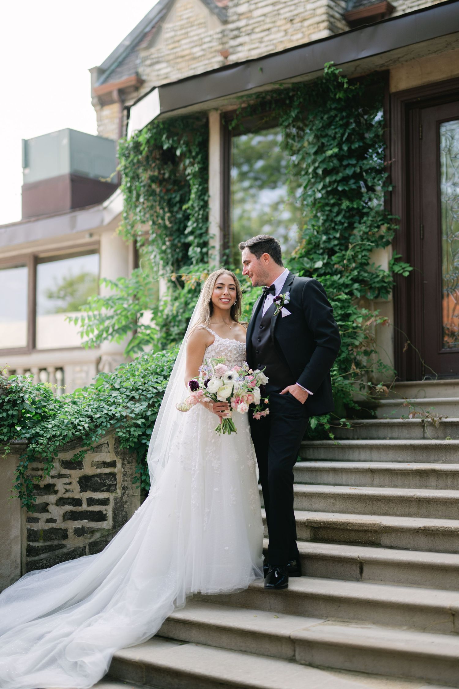 A romantic wedding couple shares tender moments on stone steps outside a historic church building. - Meyer's Castle Events