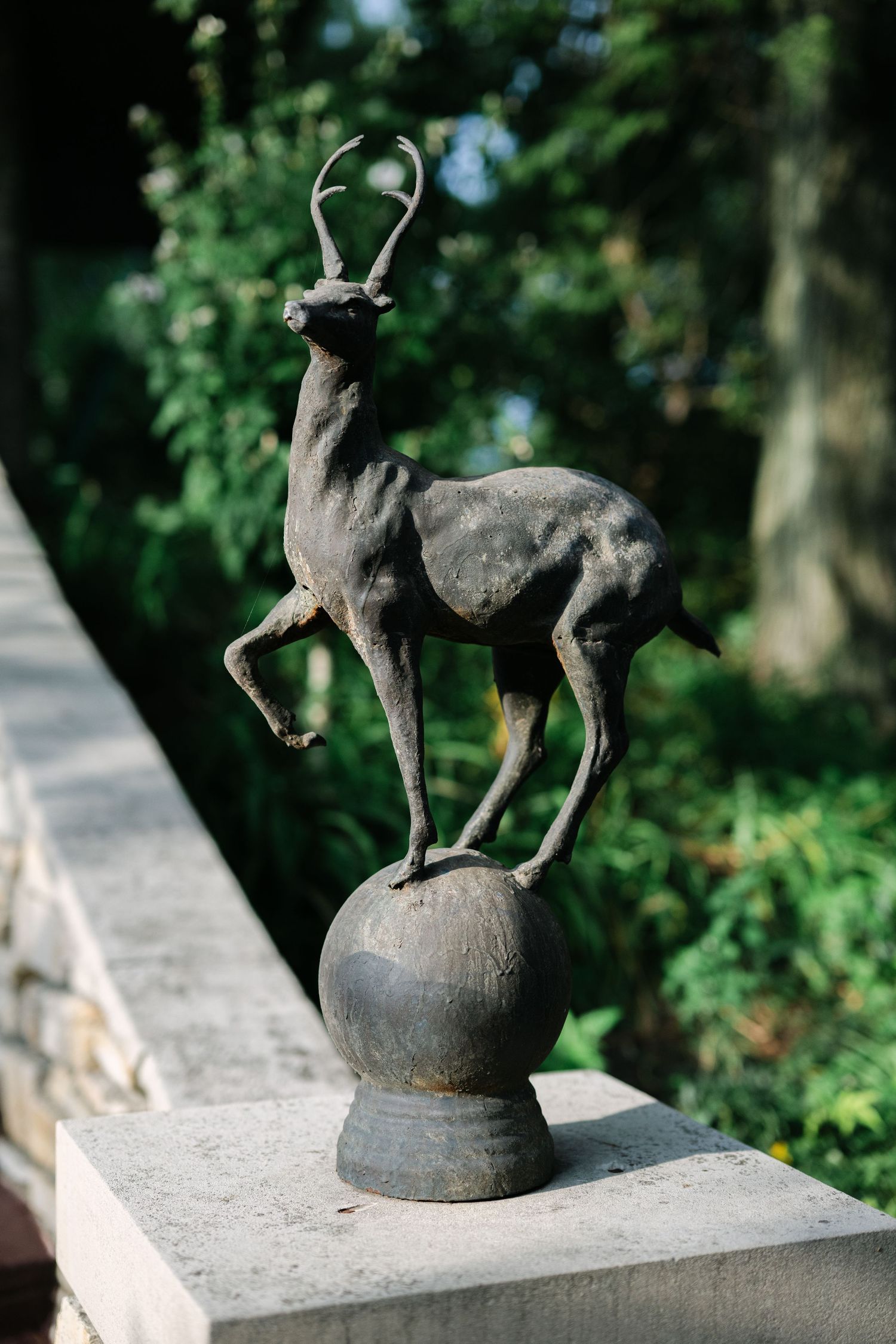 A series of bronze sculptures showing a small deer figure balanced on top of a spherical base in a garden setting. - Meyer's Castle Events