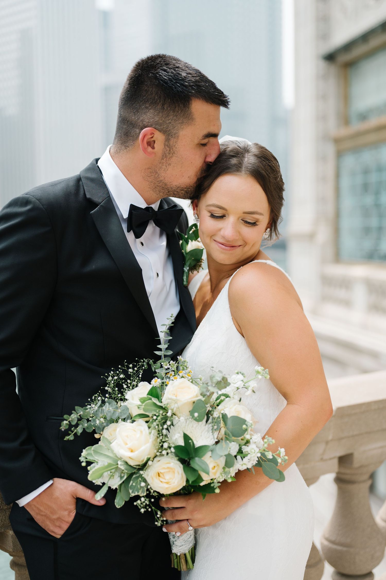 Romantic wedding moment captured on balcony with Chicago cityscape backdrop.