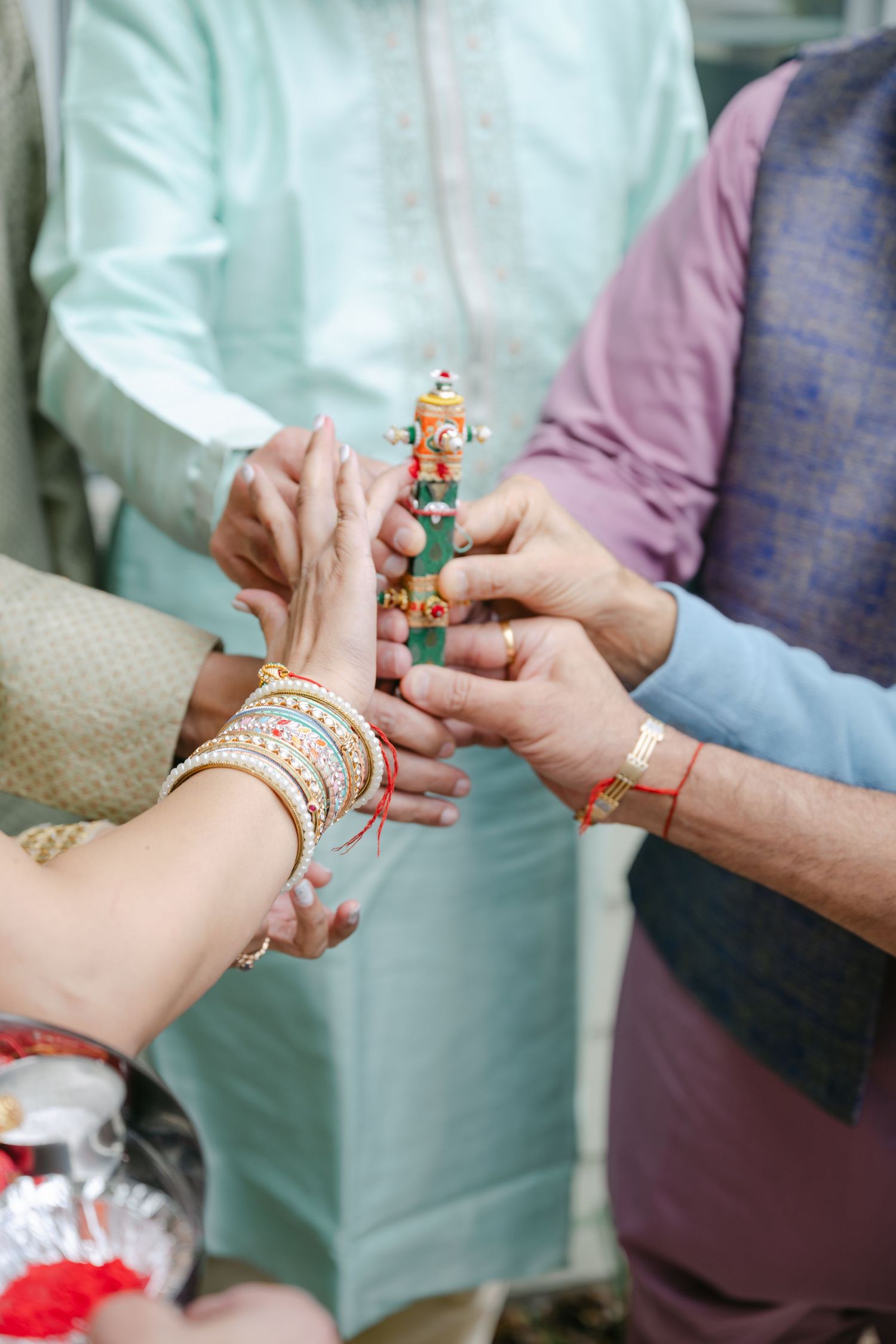 Close-up view of hands exchanging traditional Indian wedding bangles and jewelry during a ceremony ritual.