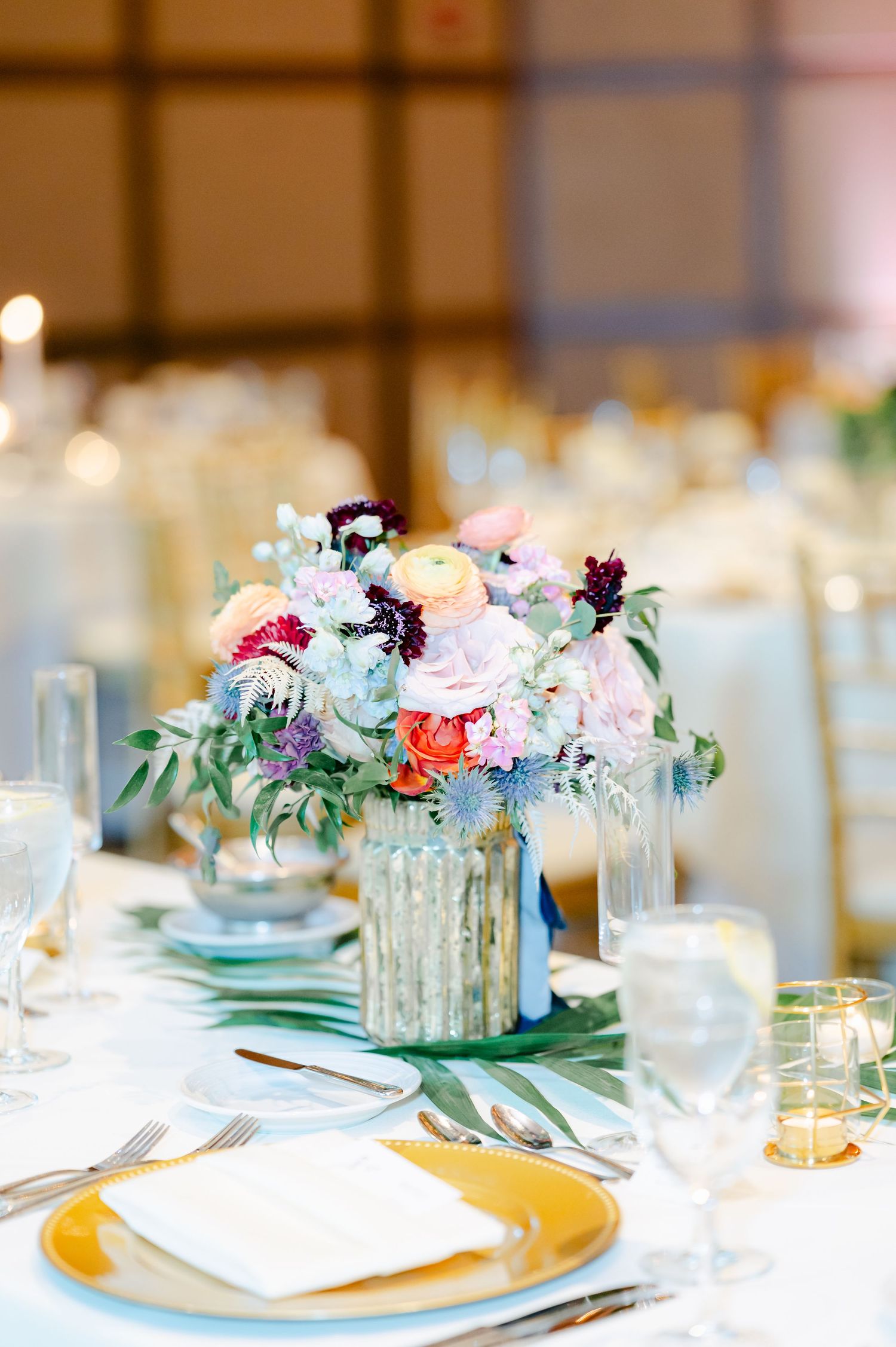 Elegant wedding table setting with mint green napkins, gold chargers, and colorful floral centerpieces. - Hyatt Lodge Oak Brook