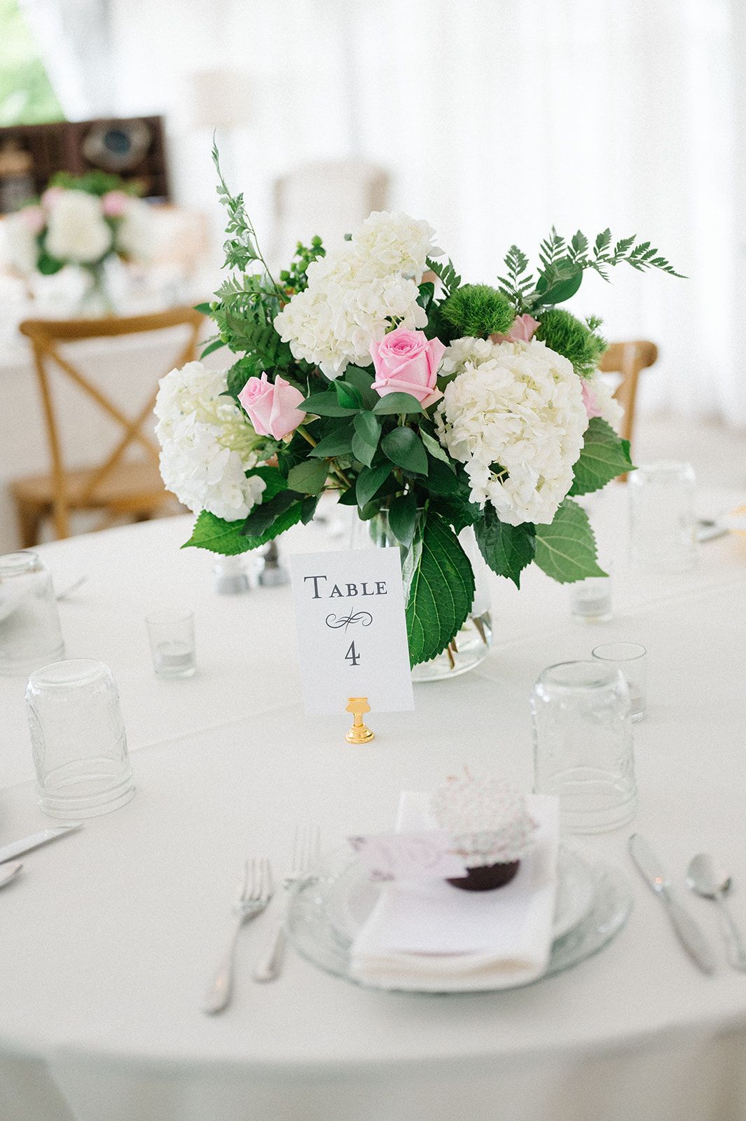 Elegant wedding reception table 4 with white hydrangeas, pink roses, greenery centerpiece. - Heritage Prairie Farm Wedding