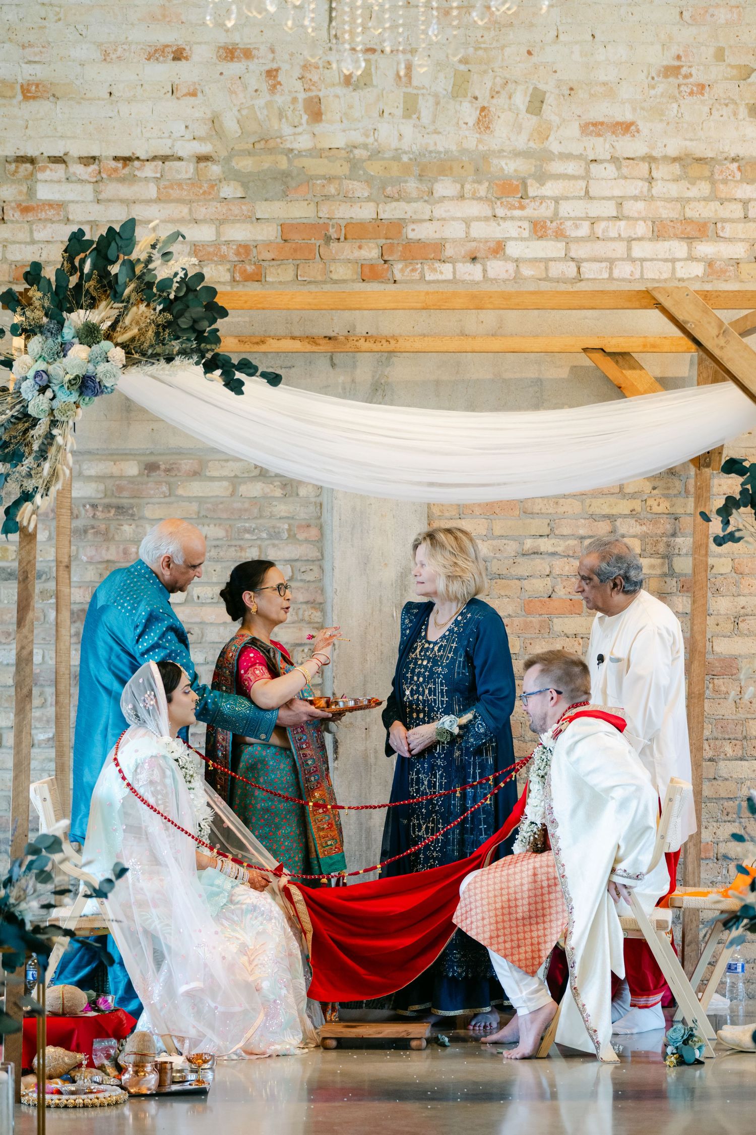 The Brix on the Fox Wedding - People in traditional dress perform a cultural dance under white fabric draped between brick walls.