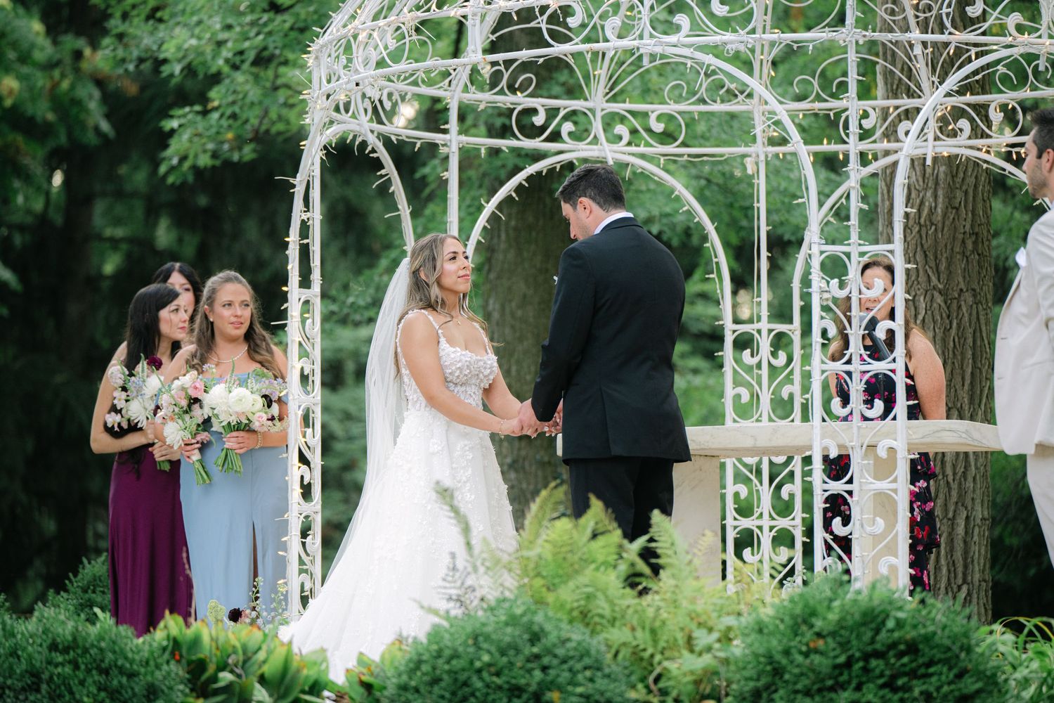 Outdoor garden wedding ceremony setup with white trellis arch and green foliage backdrop in natural setting. - Meyer's Castle