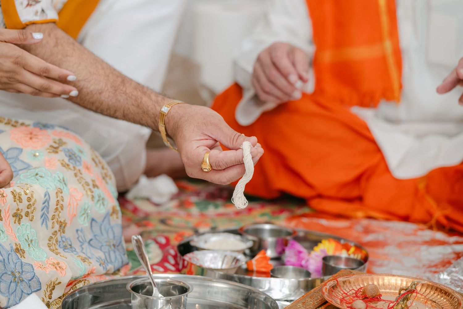 The Brix on the Fox Wedding - Close-up view of hands preparing traditional Indian food with colorful ingredients and spices on a metal tray.