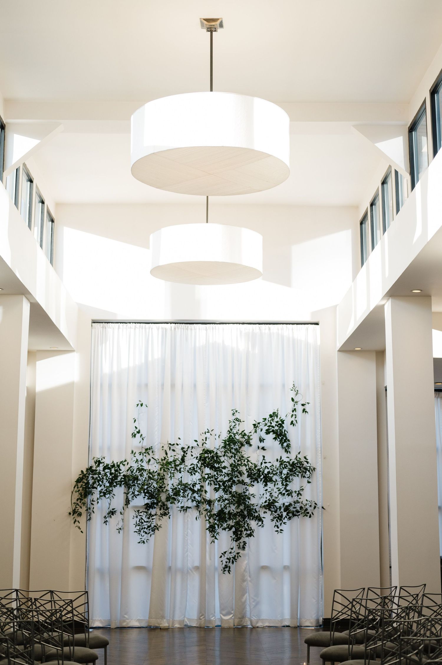 Modern white event space with round pendant lights and sheer curtains. - Chicago's Western Suburbs Wedding