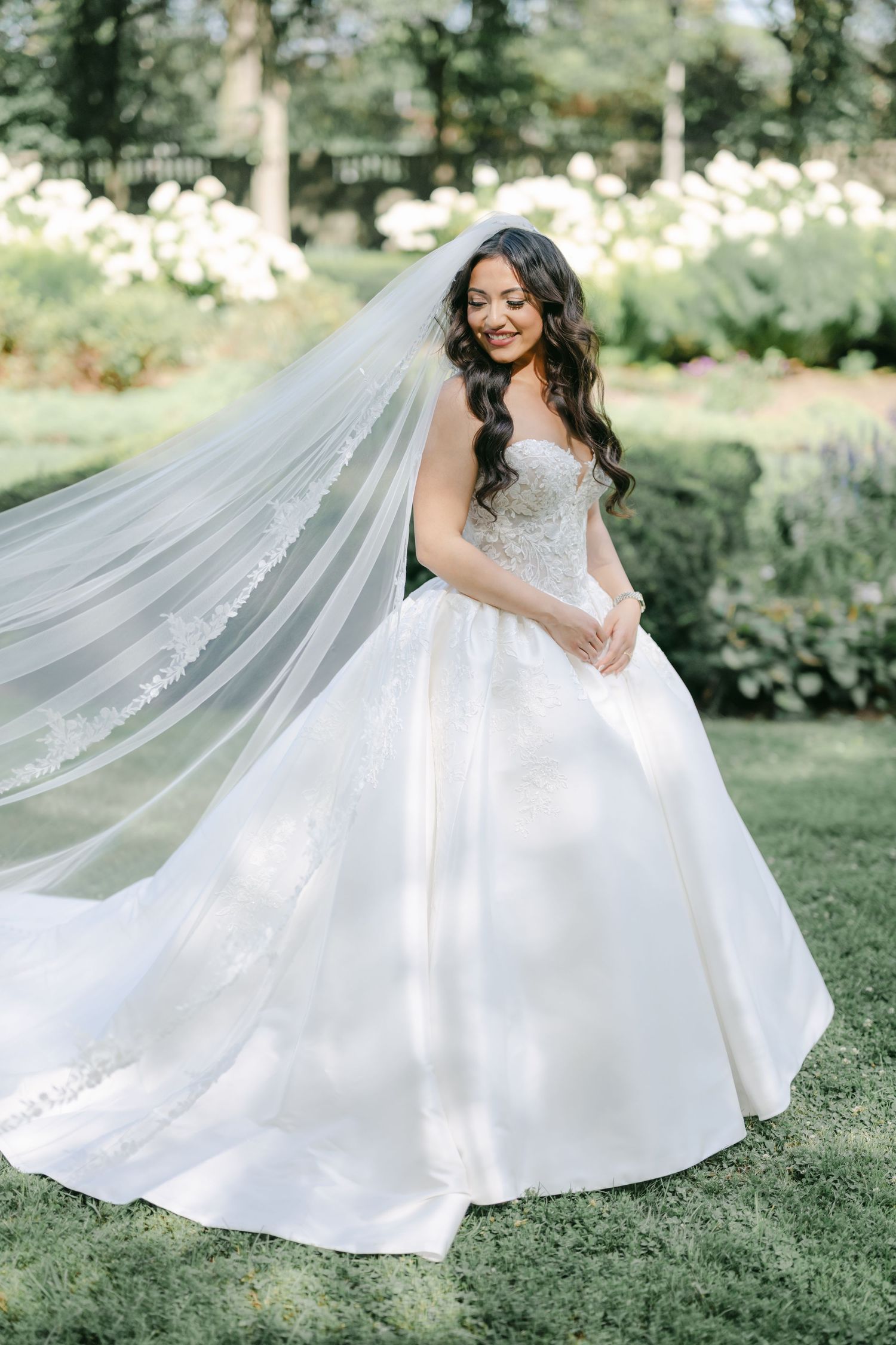 A flowing white wedding dress twirls gracefully in a garden setting. - LM Studio Chicago