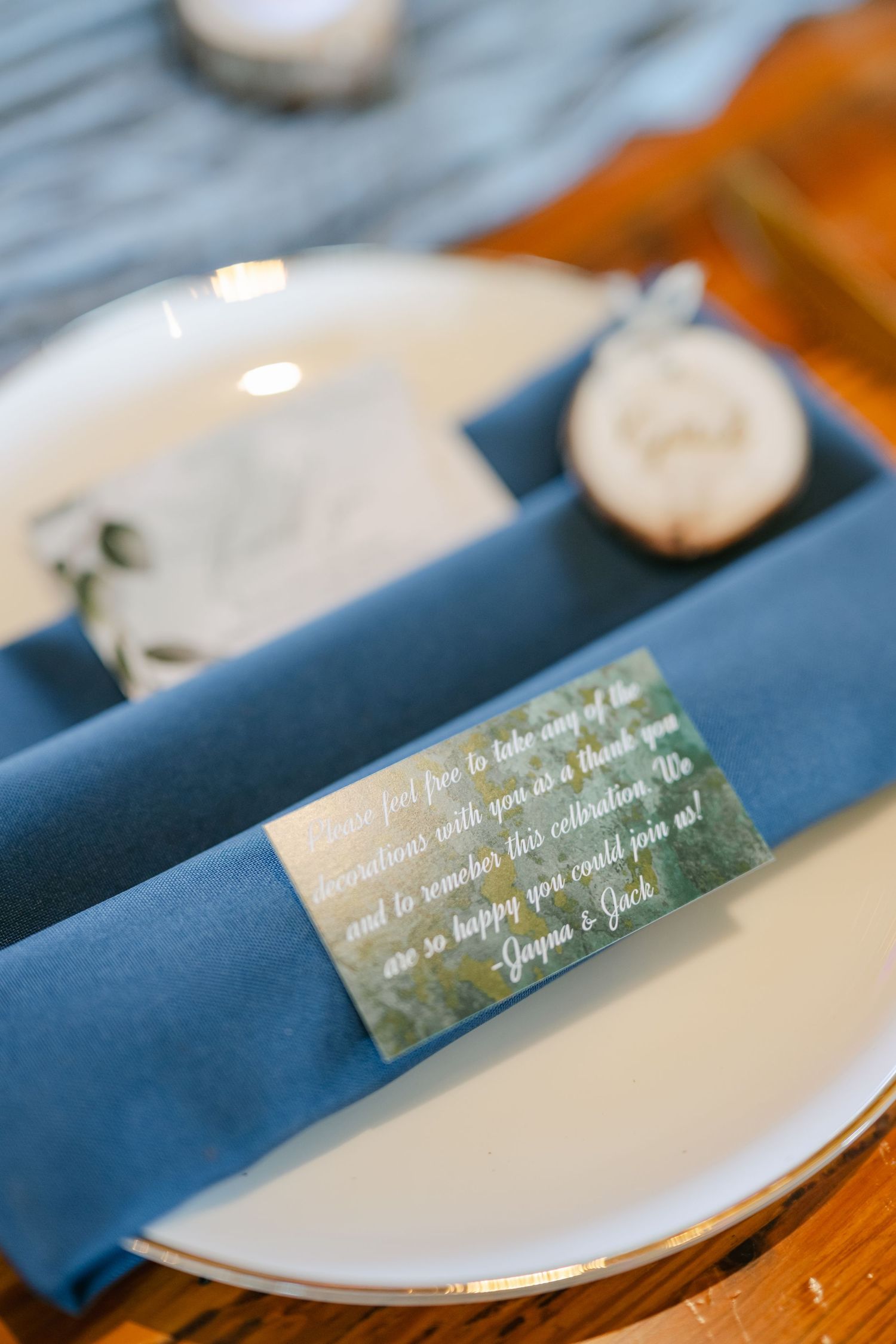 White place settings with navy blue napkins and handwritten place cards on a wooden table at an elegant event. - The Brix on the Fox