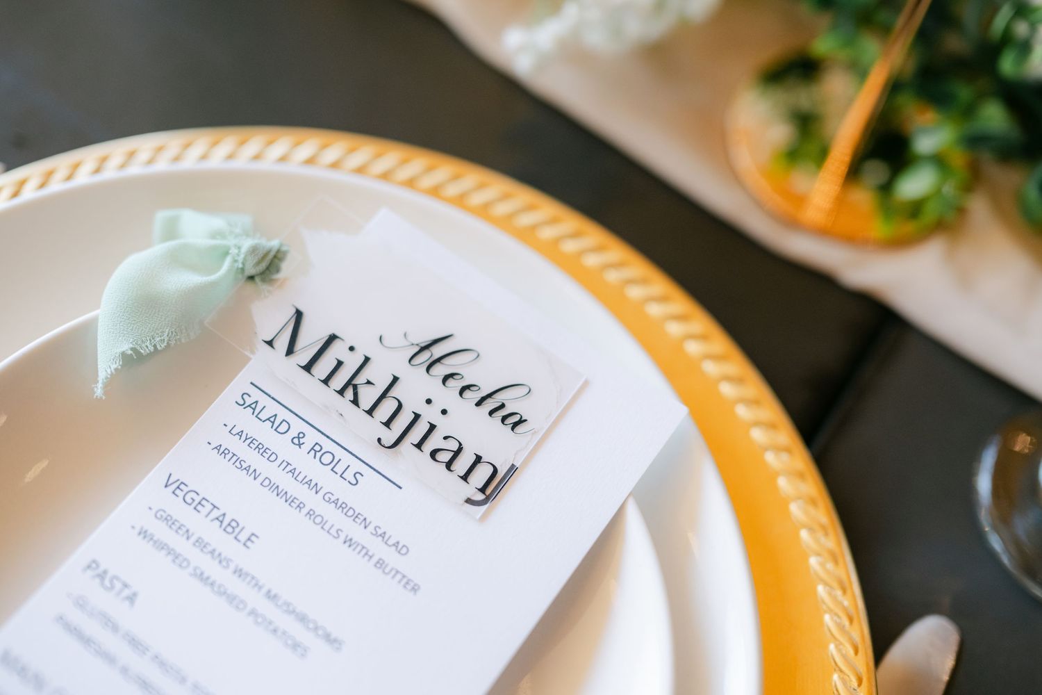 Elegant wedding place setting with a gold charger plate, mint ribbon, and personalized menu card. - Youngblood Vineyard Wedding