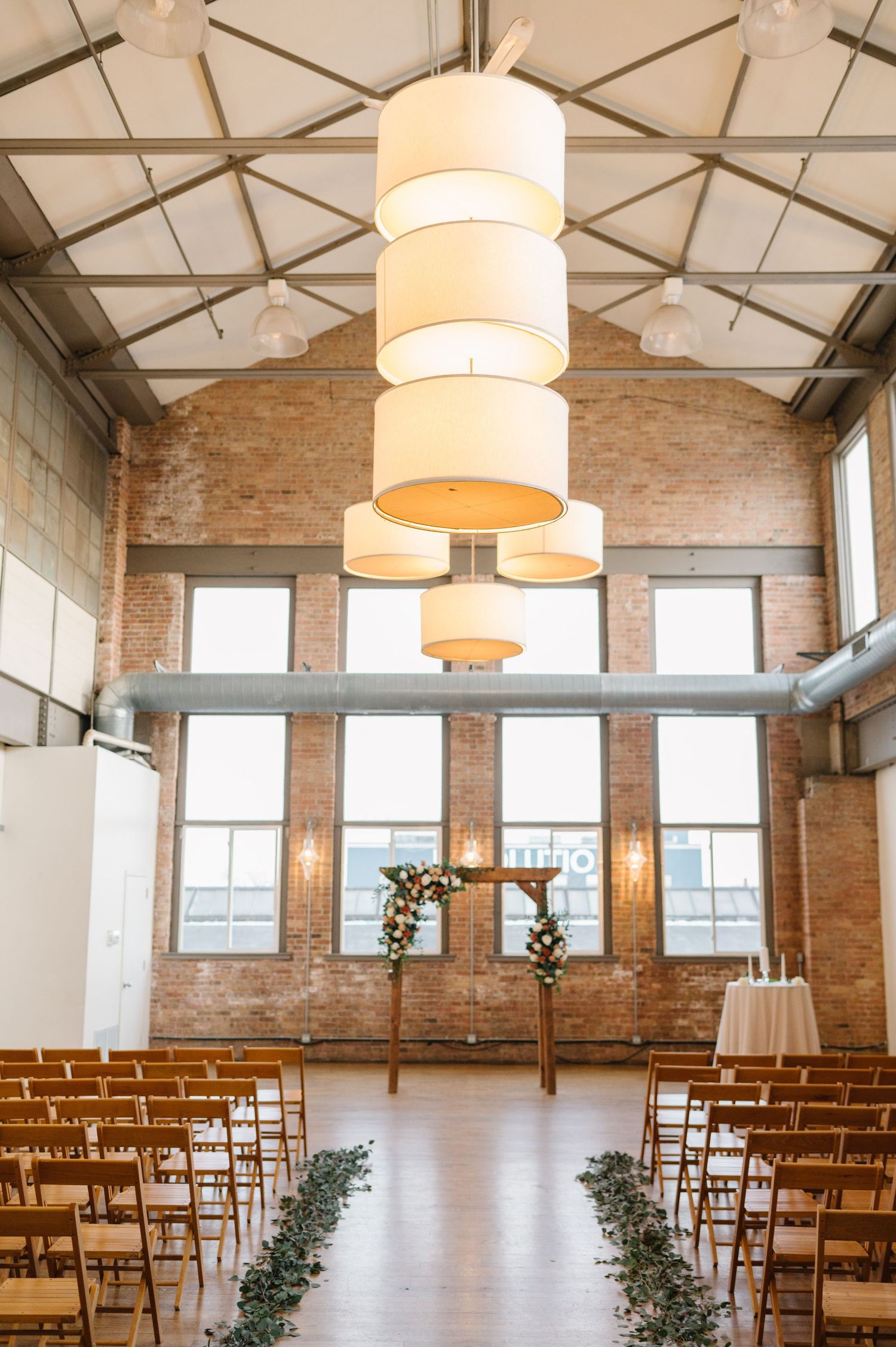 Industrial loft wedding venue with exposed brick walls, wooden chairs. - Chicago's Western Suburbs Wedding