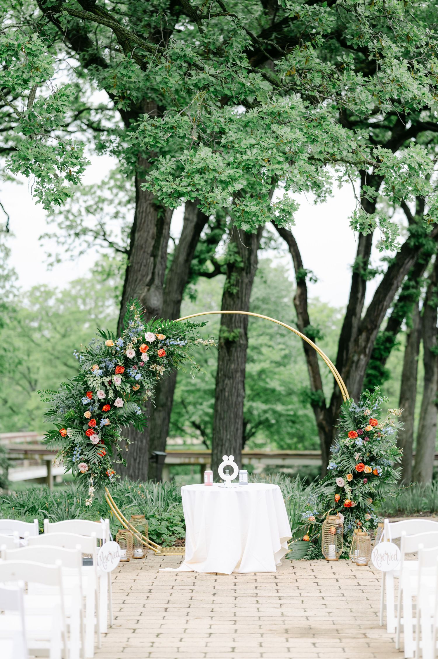 Modern circular wedding arch with coral and pink floral arrangements on a brick paved outdoor ceremony space. - Hyatt Lodge Oak Brook