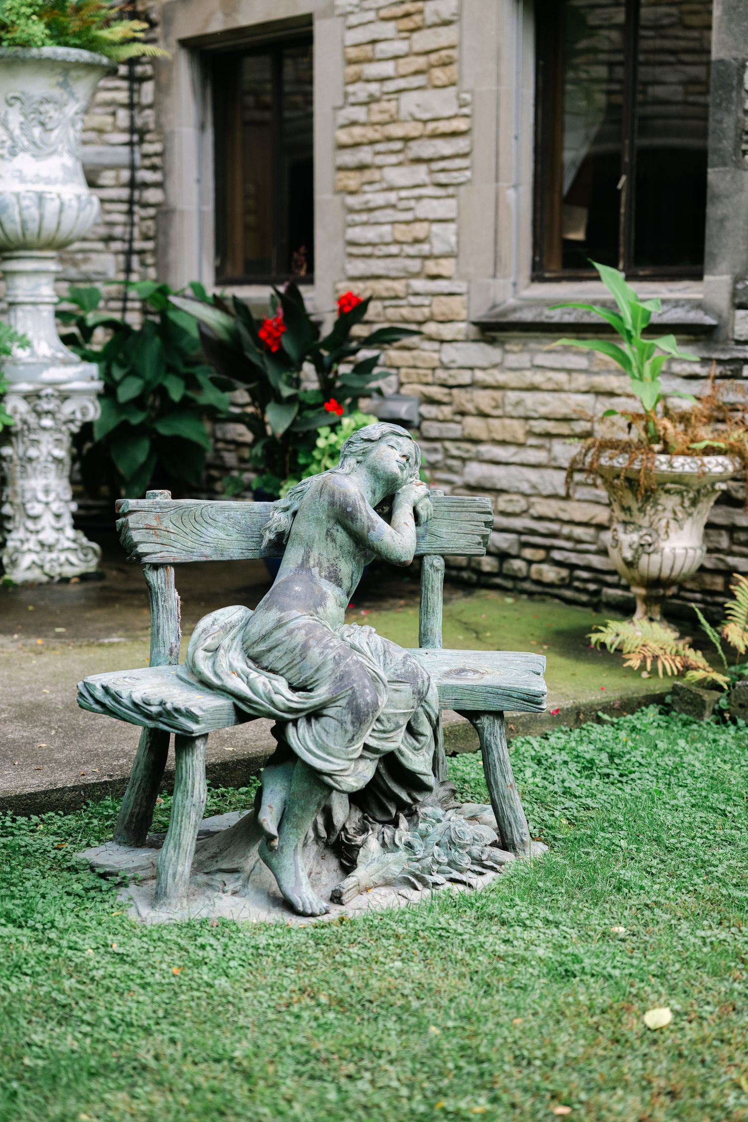 Stone garden bench with ornate rooster sculptures adorns a grassy lawn outside a rustic stone building. - Meyer's Castle Events