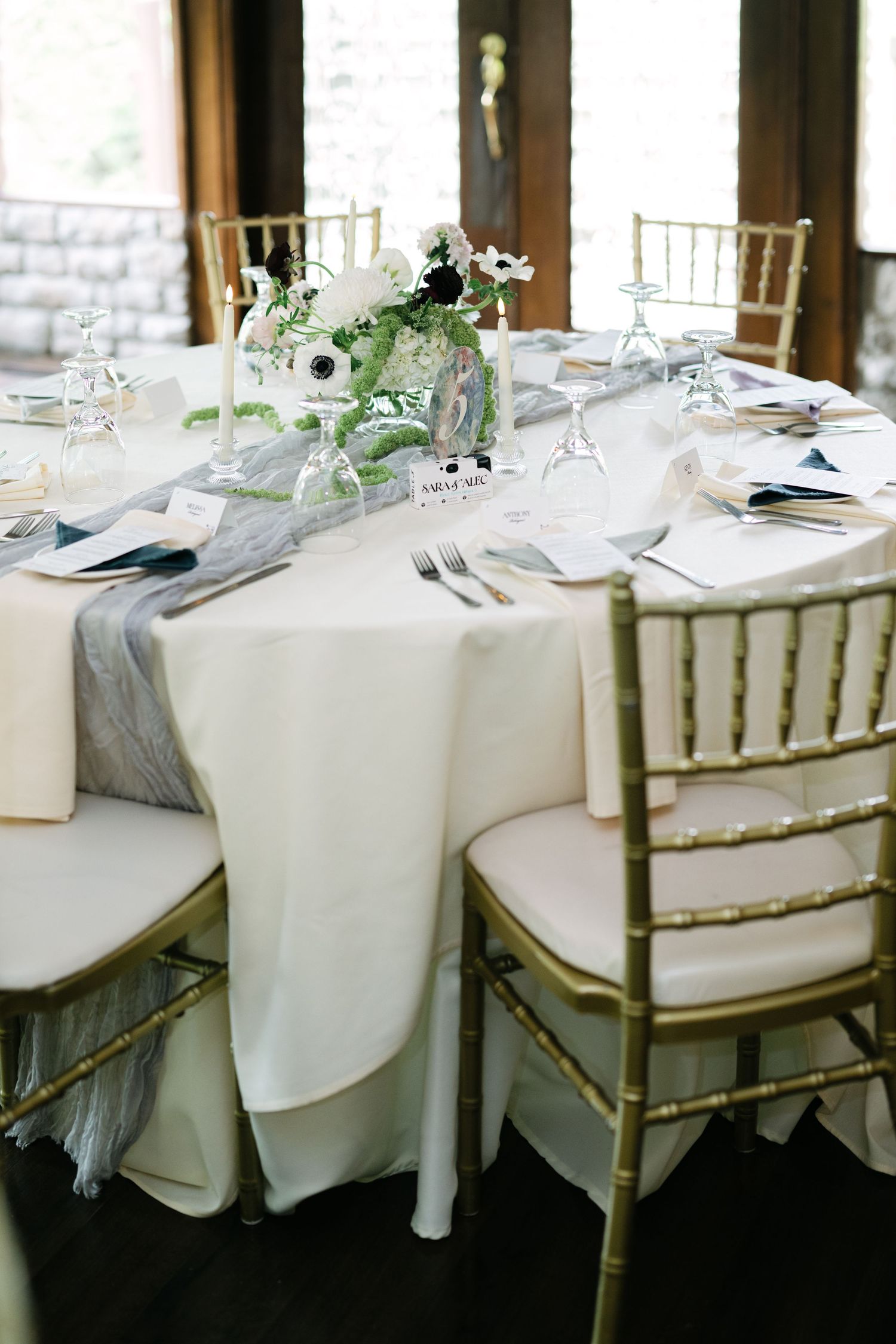 Elegant wedding reception table setting with white linens, gold chiavari chairs and delicate floral centerpieces. - Meyer's Castle Events