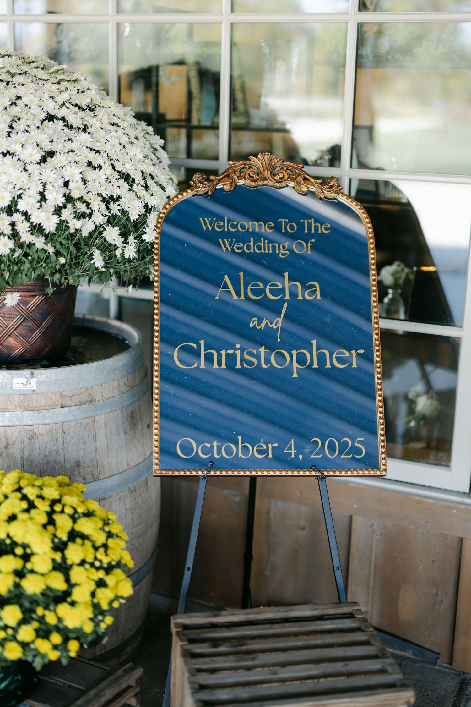 Elegant blue and gold wedding welcome sign for Aleeha and Christopher Wedding displayed on easel with floral decor. - Youngblood Vineyard