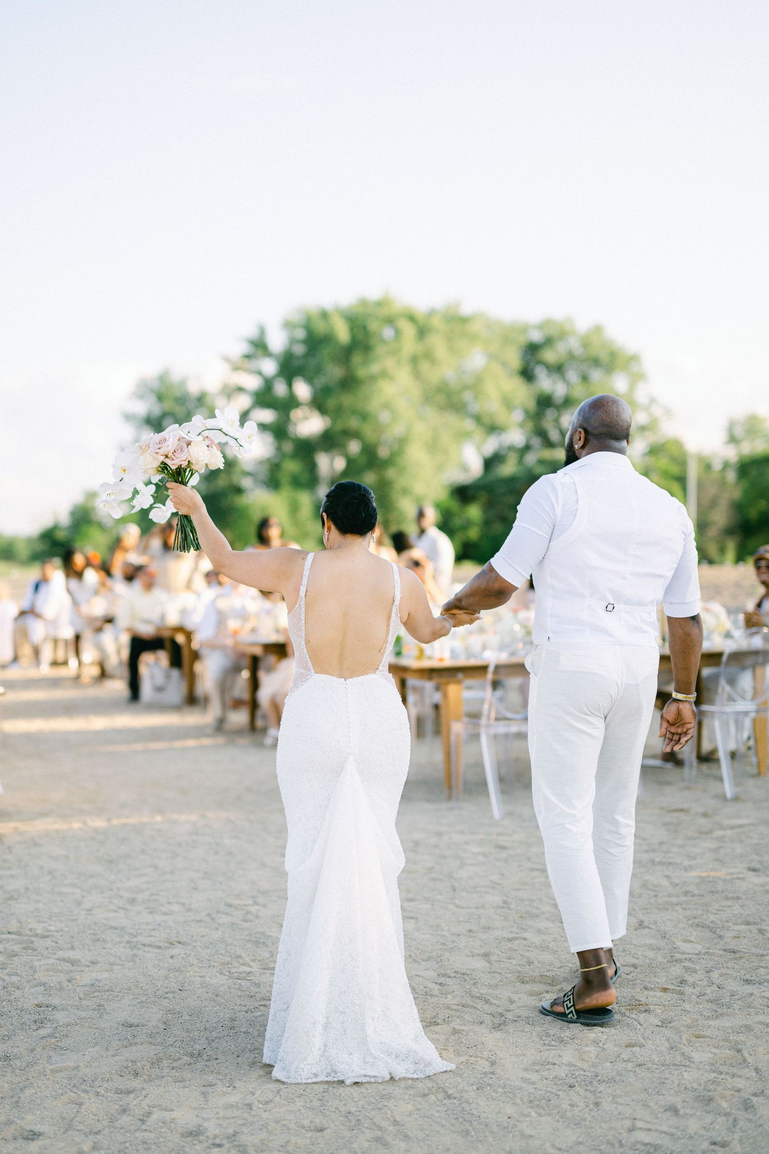 Newlyweds in elegant white attire celebrate during their outdoor beach wedding reception. - Chicago Beach Wedding