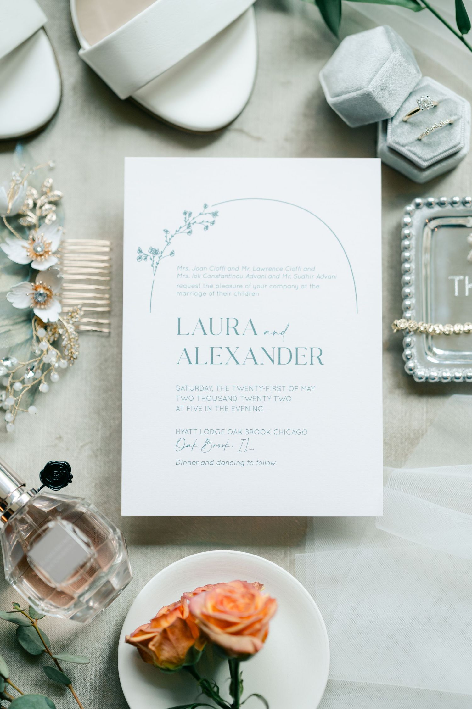 Elegant wedding stationery flatlay with white invitations, roses, perfume bottles, and delicate accessories. - Hyatt Lodge Oak Brook