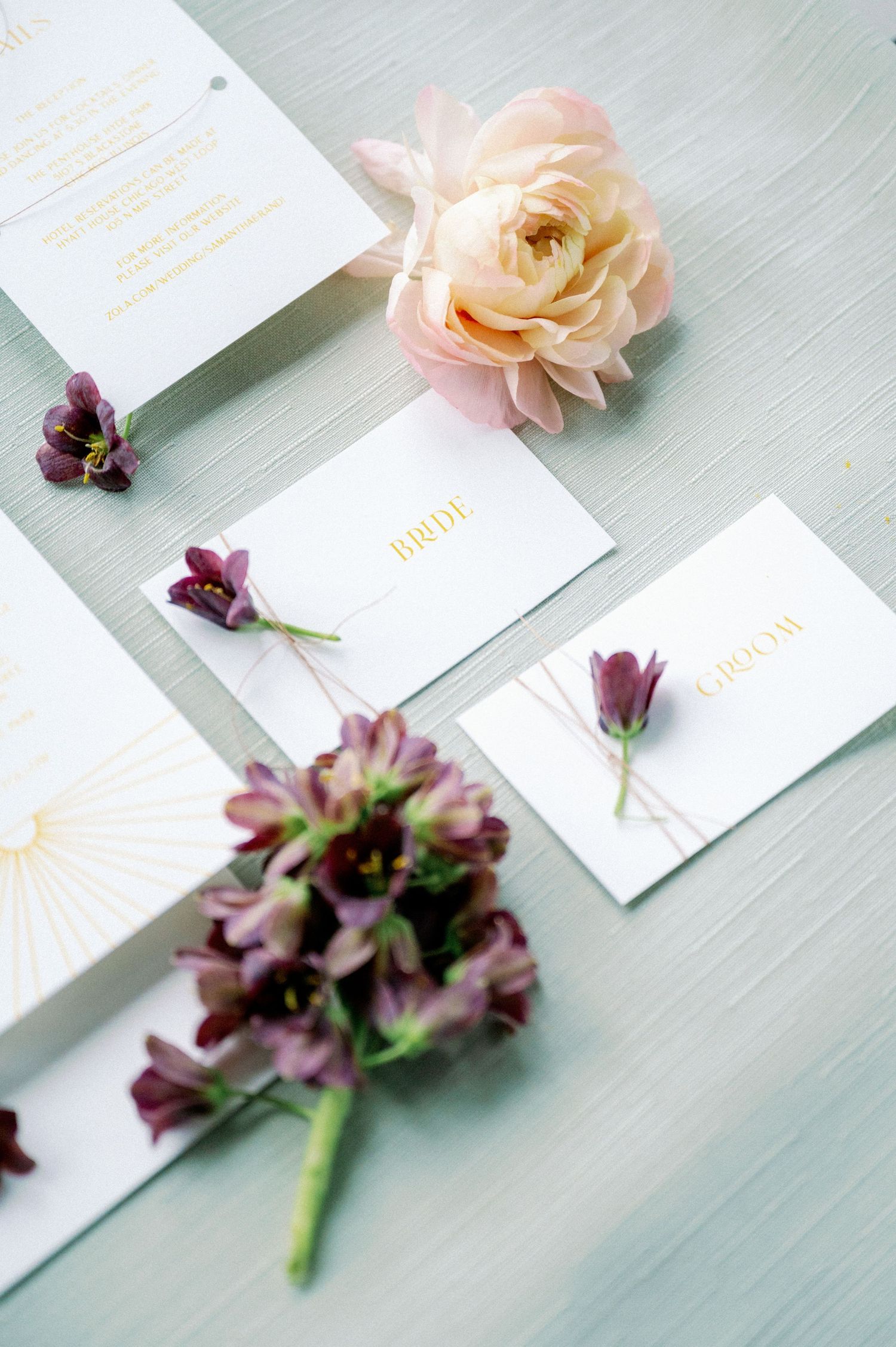 Delicate floral arrangements with purple and peach blooms laid out with white cards on a soft mint green surface.