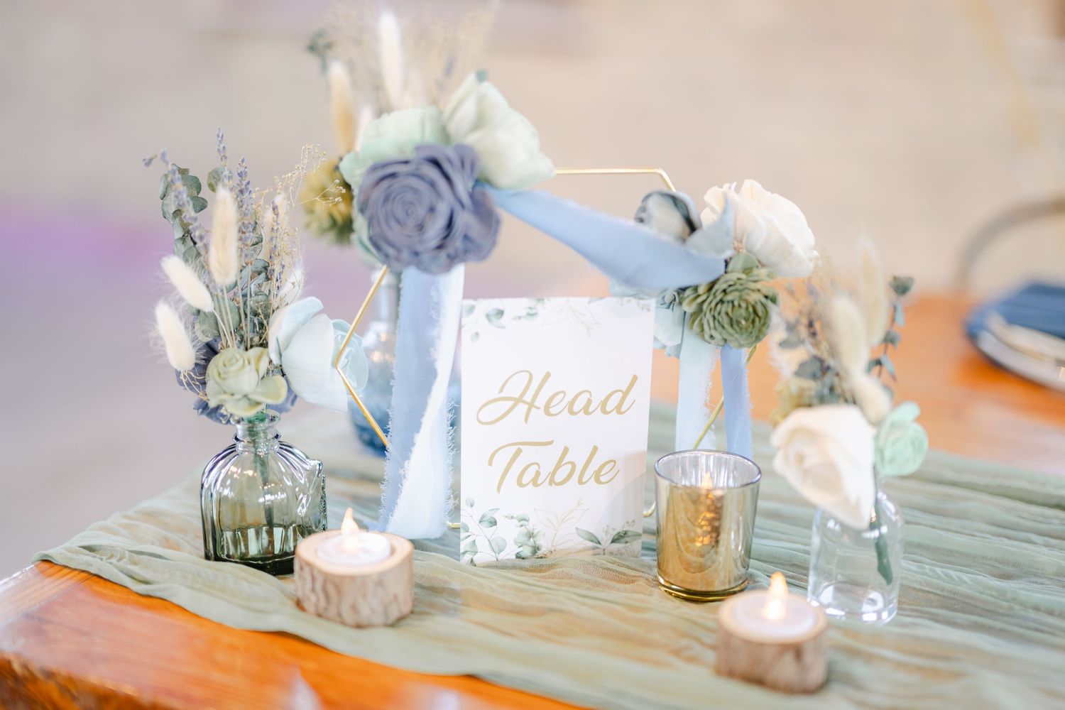 Elegant wedding table decorations with soft blue and white floral centerpieces in glass vases on mint-colored linens. - The Brix on the Fox